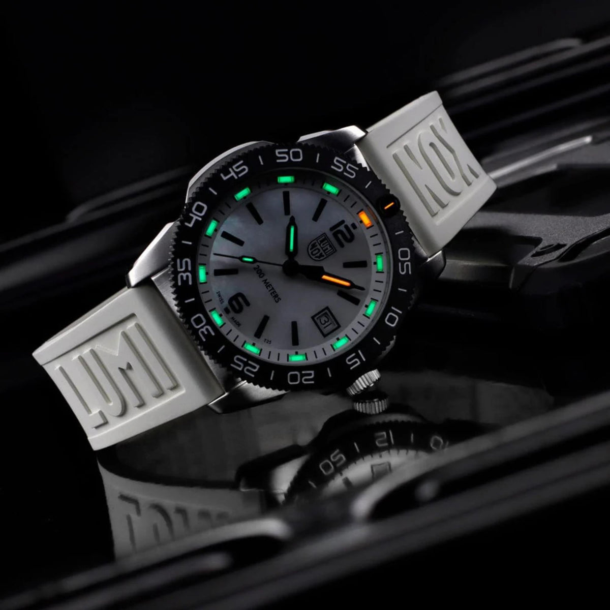 Close-up diver watch with white dial, luminous green and orange hands and markers