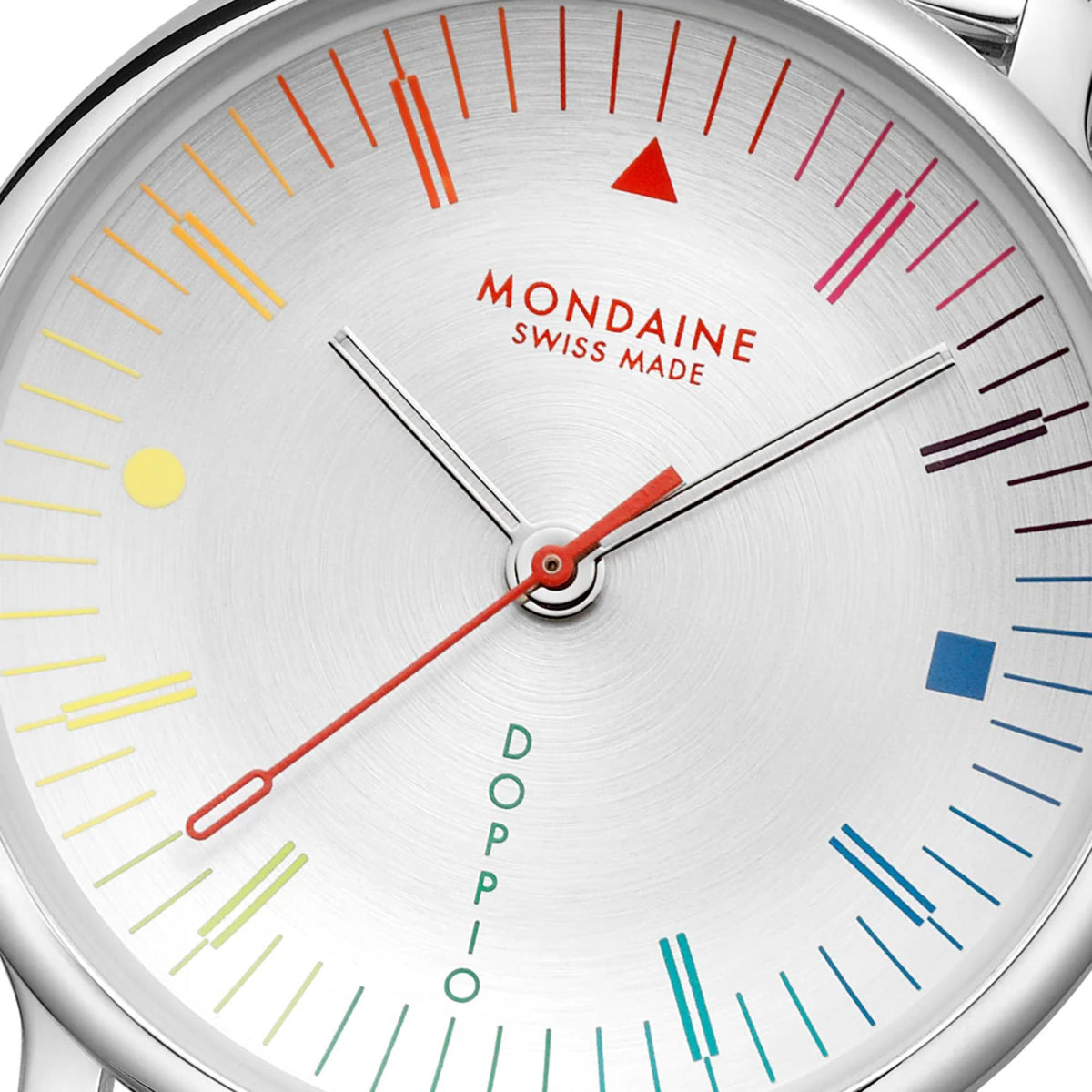 Close-up of Mondaine Doppio watch face, highlighting the brushed silver dial texture, red second hand, and primary color geometric accents