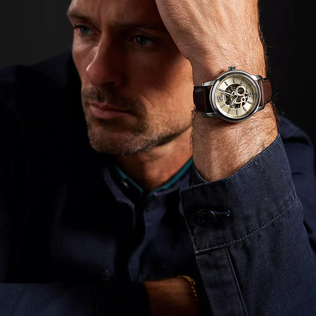 On-wrist view of Fossil Heritage ME3264 mens timepiece showcasing the cream skeleton dial, silver casing, and brown strap