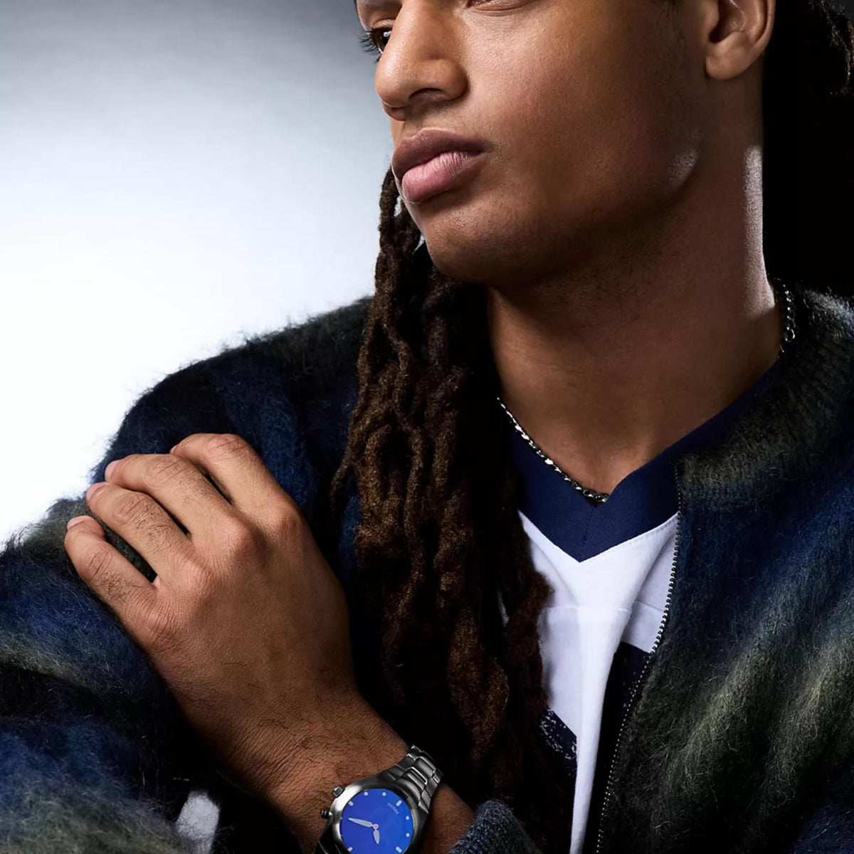 Stainless steel watch with blue dial and gold hands on wrist under jacket