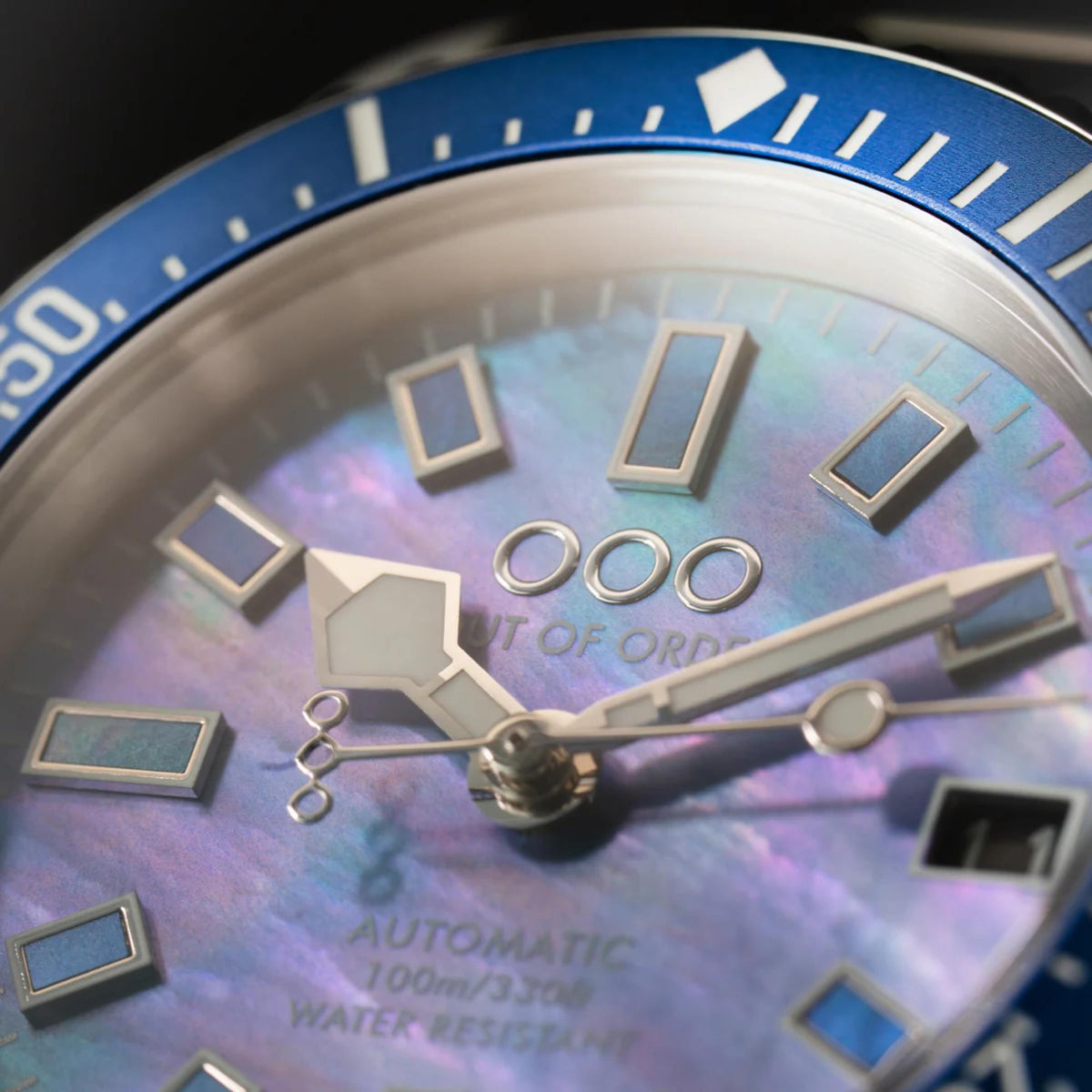 Blue mother-of-pearl dial close-up with skeleton hands and geometric hour markers