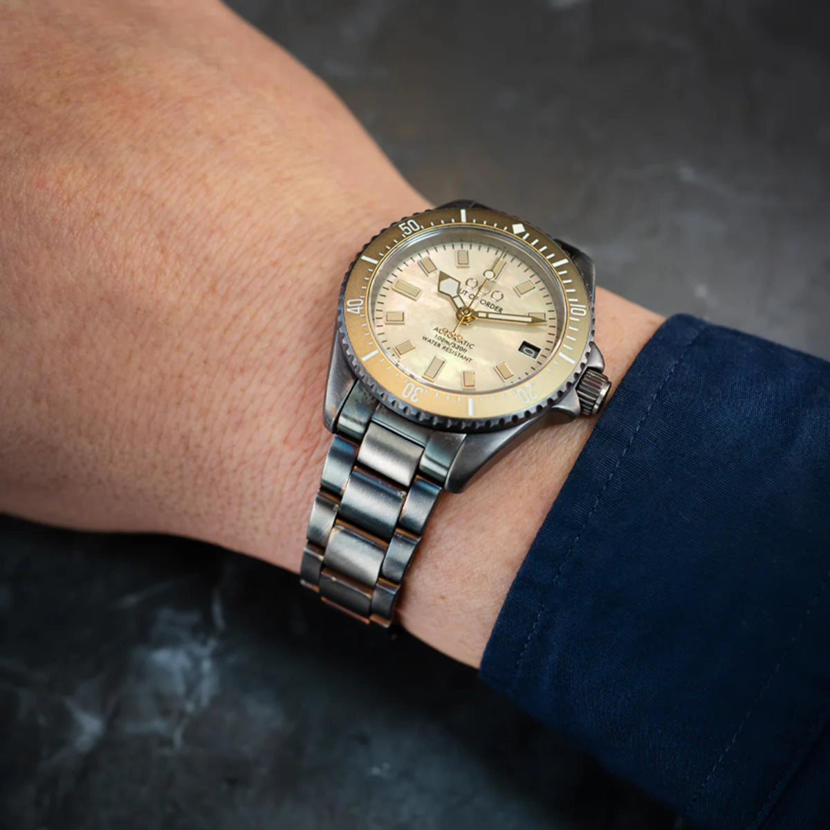 Men's automatic wristwatch on wrist with ivory mother-of-pearl dial and steel band