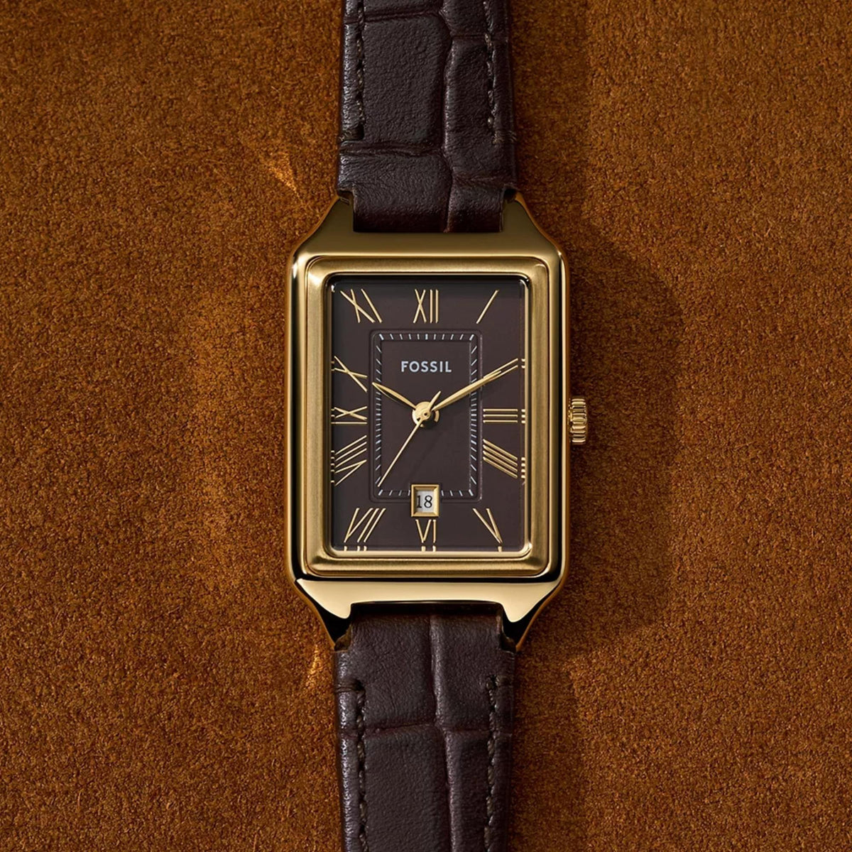 Top-down view of Fossil Raquel ES5367 resting on a textured surface, detailing the brown dial, Roman numerals, and date window