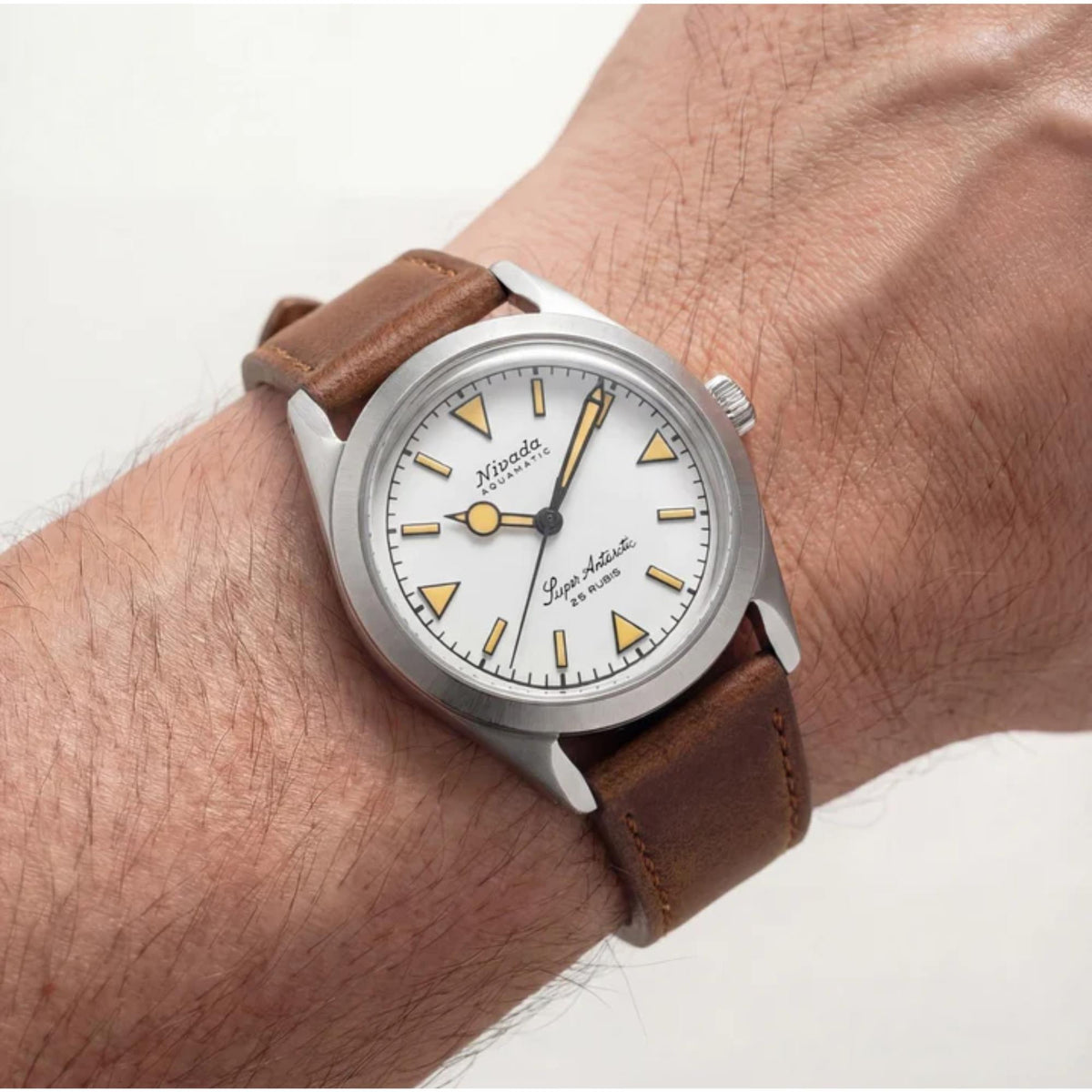 A lifestyle wrist shot of a Nivada Grenchen watch with a white dial, styled with the 20mm Brown Leather Strap NZ16AB