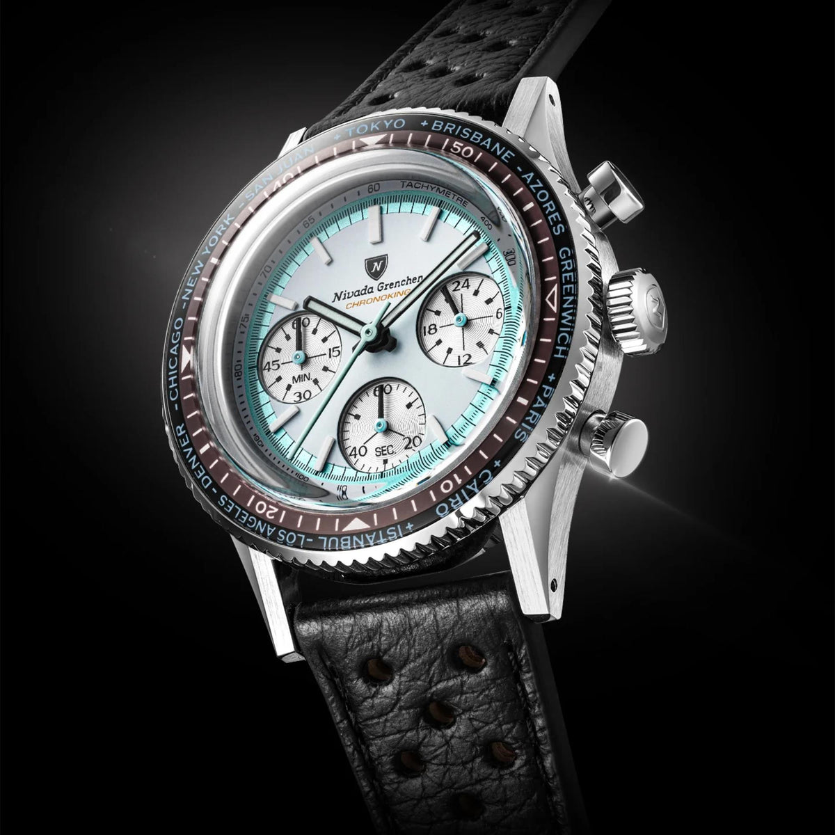Nivada Grenchen Chronoking watch with a silver-toned metal case, a white dial with its subdials, a black tachymeter bezel, and a black leather strap, photographed on a dark studio background
