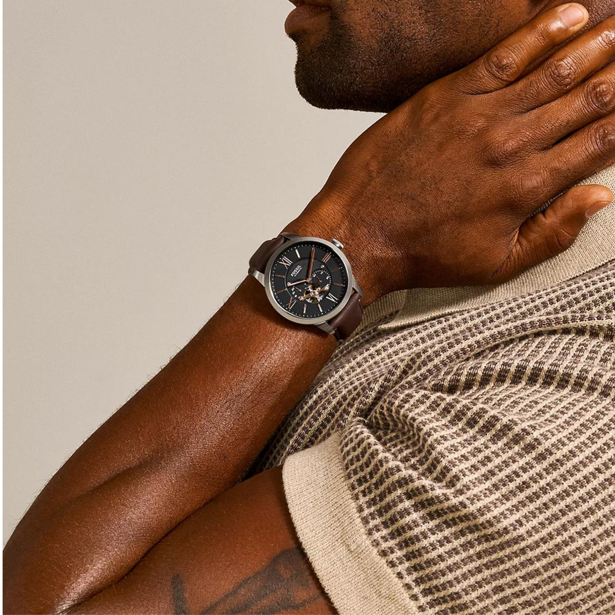 On-wrist perspective of the Fossil Townsman ME3061 wrist watch showcasing the black open heart dial paired with rose gold-tone indices and brown leather band