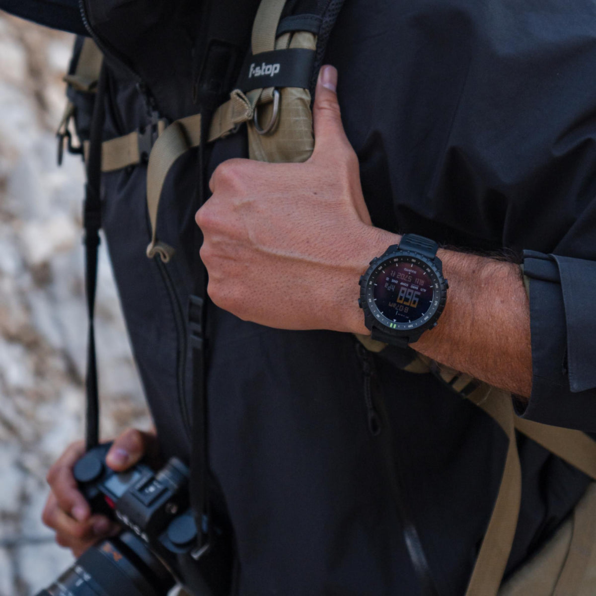 Black rugged digital watch with silicone strap, shown on wrist with lit screen
