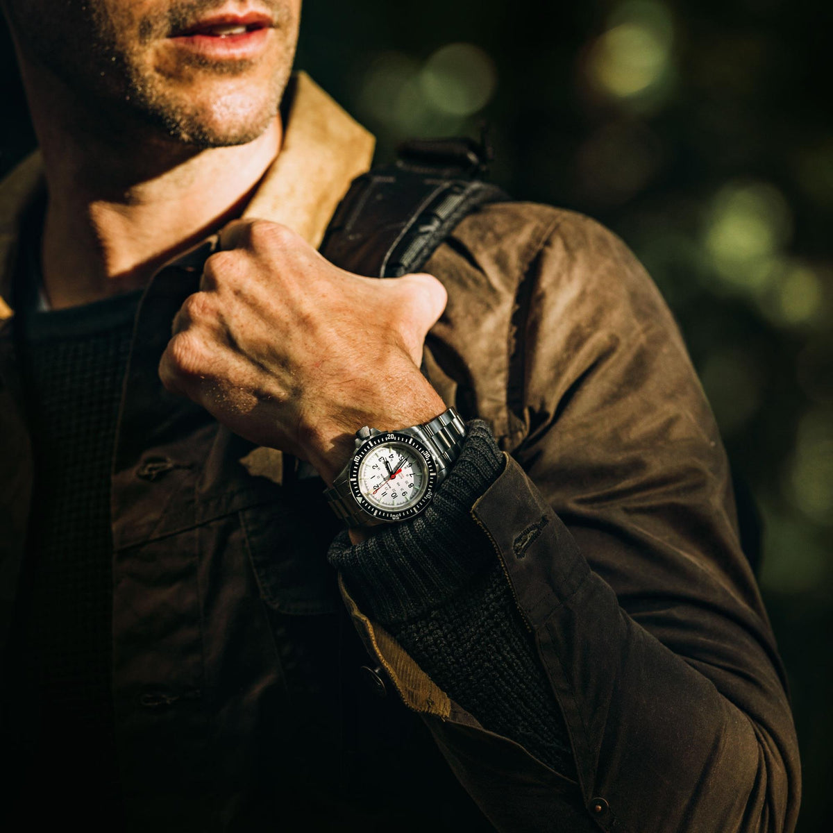 Marathon GSAR Arctic Edition WW194006SS-0513 automatic wrist watch worn by a man holding a backpack strap outdoors