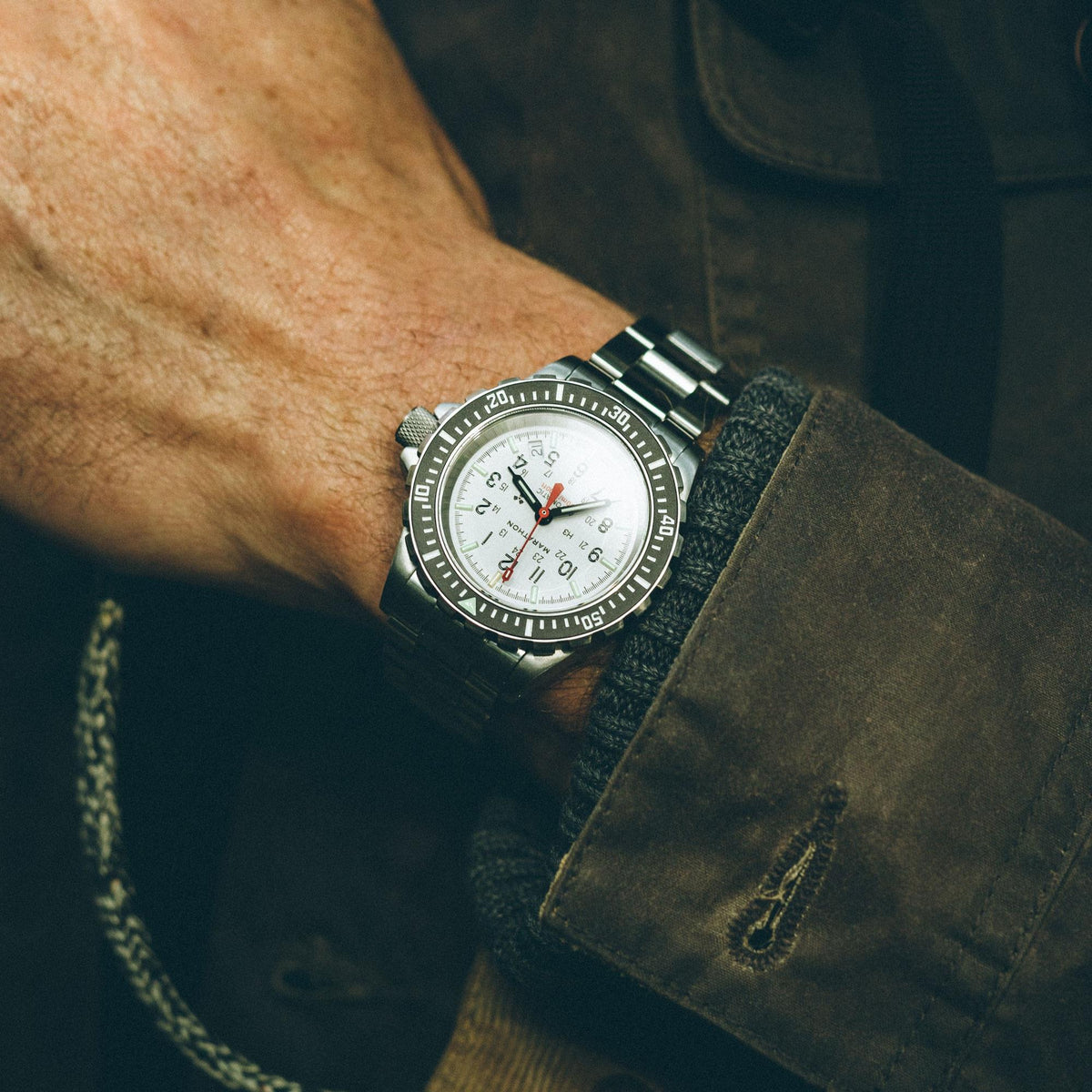 Marathon GSAR Arctic Edition WW194006SS-0513 mens automatic watch showing white dial peeking out from a jacket cuff