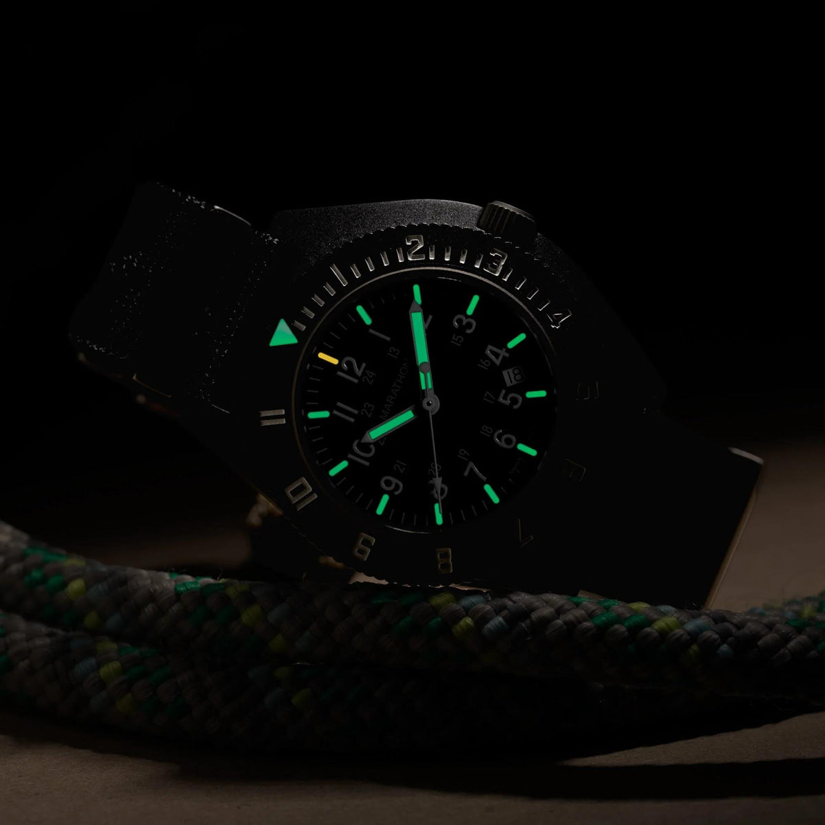 Marathon Navigator WW194013BK-2102 quartz timepiece displaying illuminated dial features resting on coiled rope