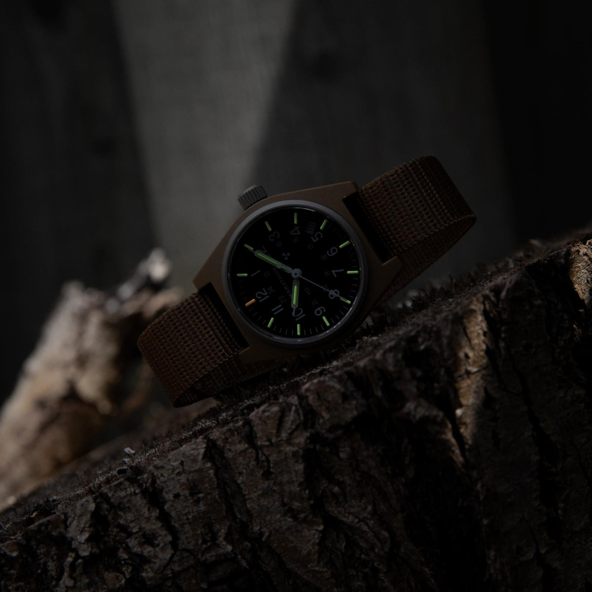 Marathon General Purpose Field WW194015DT-0103 quartz watch displaying glowing dial markers resting on tree bark