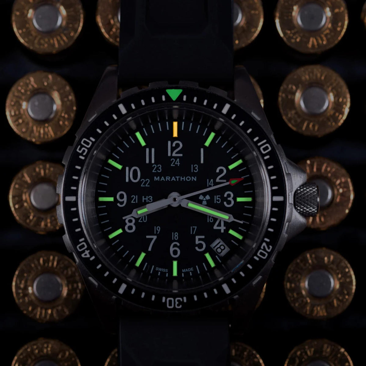 Marathon MSAR WW194027SS-0130 quartz watch macro shot displaying illuminated tritium markers on 36mm black dial in a dark setting