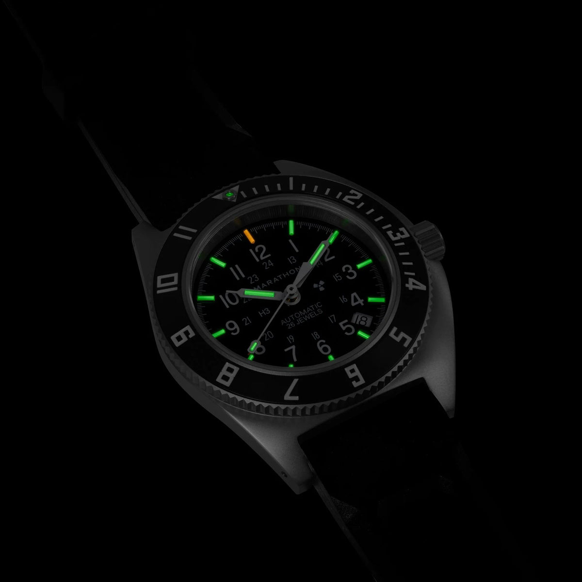 Marathon Navigator SSNAV-D automatic watch showing illuminated tritium markers on black dial in pitch darkness