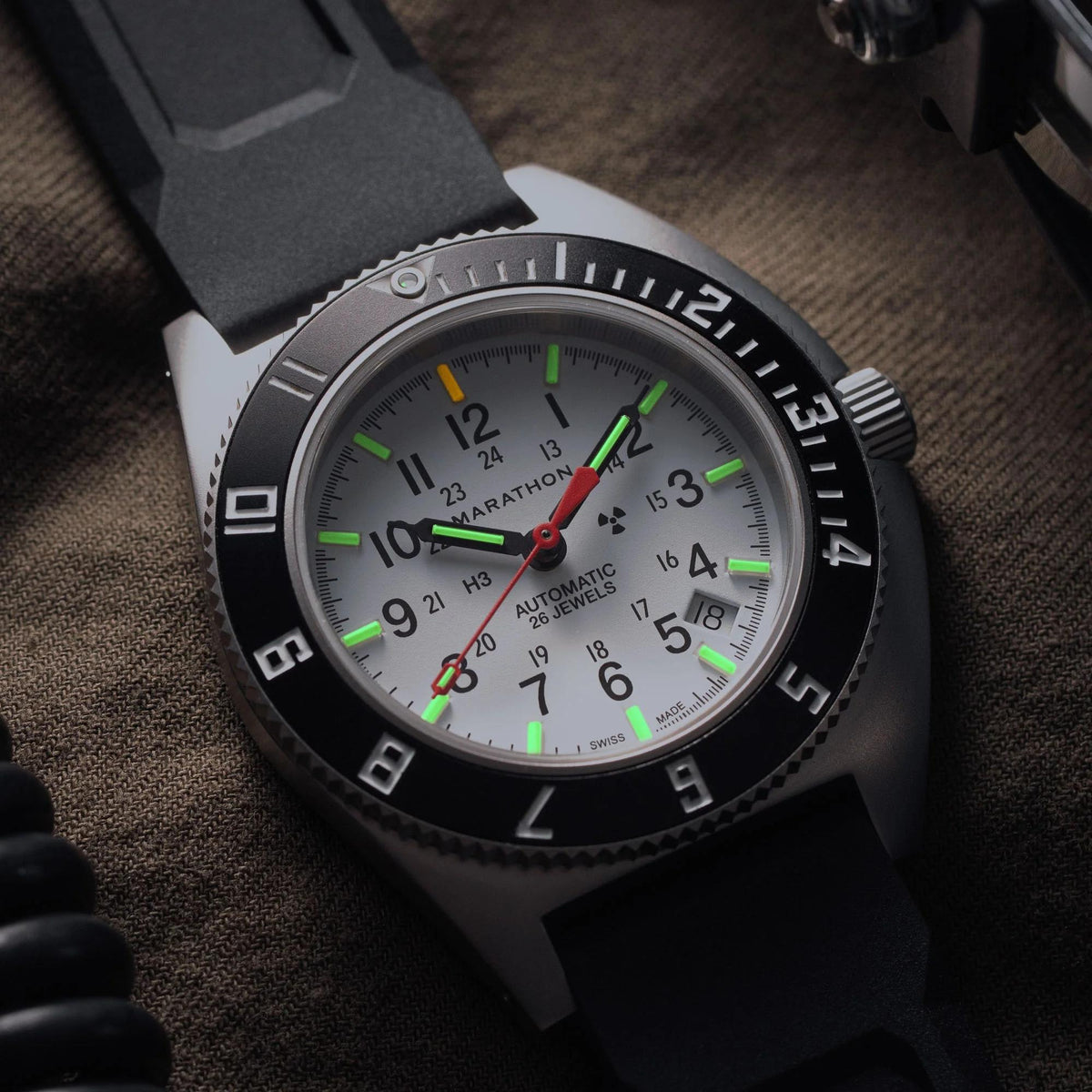 Marathon Navigator Arctic watch showing glowing tritium gas tubes on white dial in low light