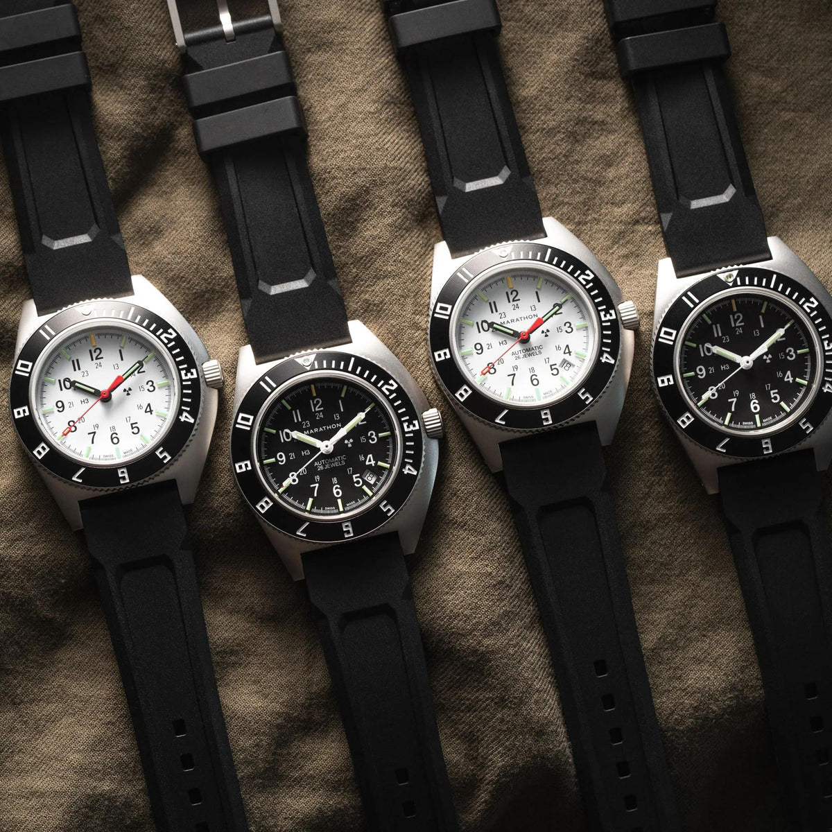 Marathon Navigator Arctic SSNAV-D WW194030SS-0530 watch alongside matching watches with black rubber straps on a textured background