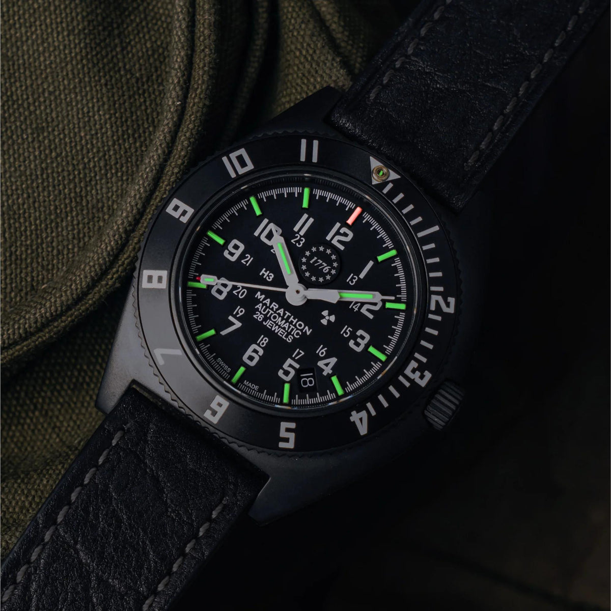Marathon Steel Navigator with Date WW194030AN-US250 automatic watch showing glowing illuminated markers and hands on black dial in dark setting