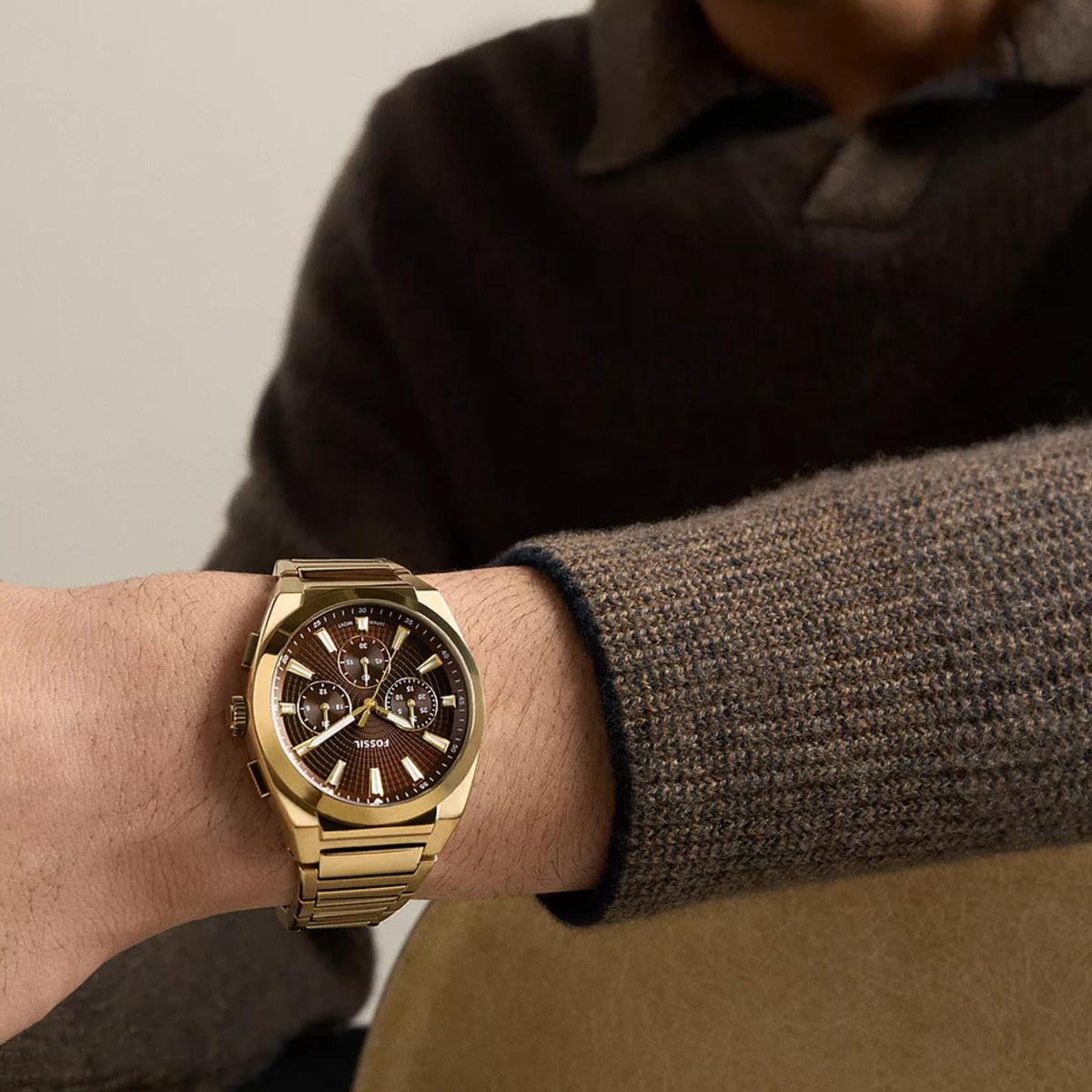 Fossil Everett FS6184 mens quartz timepiece on wrist showcasing brown dial and gold-tone metal bracelet
