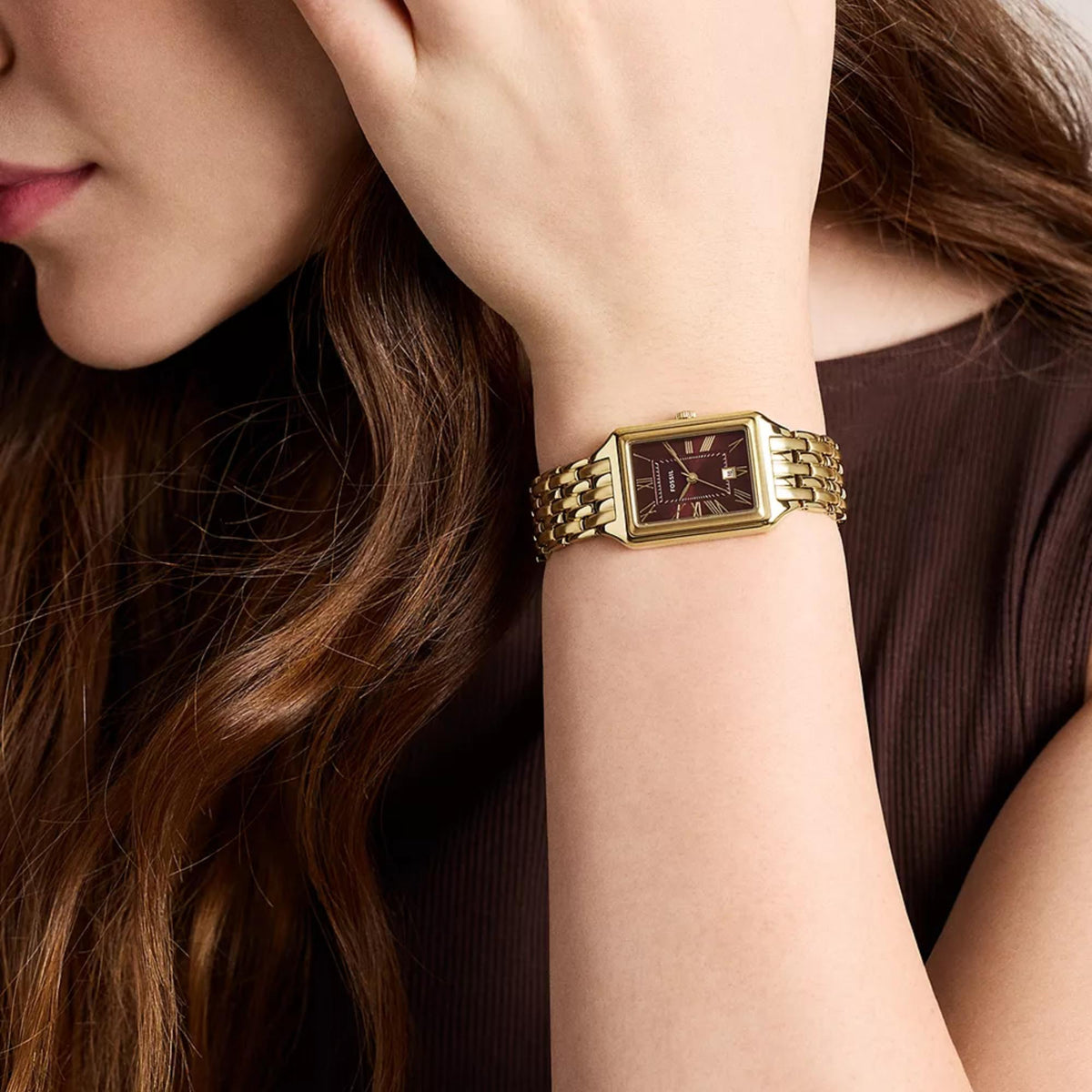 Fossil Raquel ES5512 womens quartz watch on wrist featuring red dial with gold rectangular case and gold-tone link bracelet