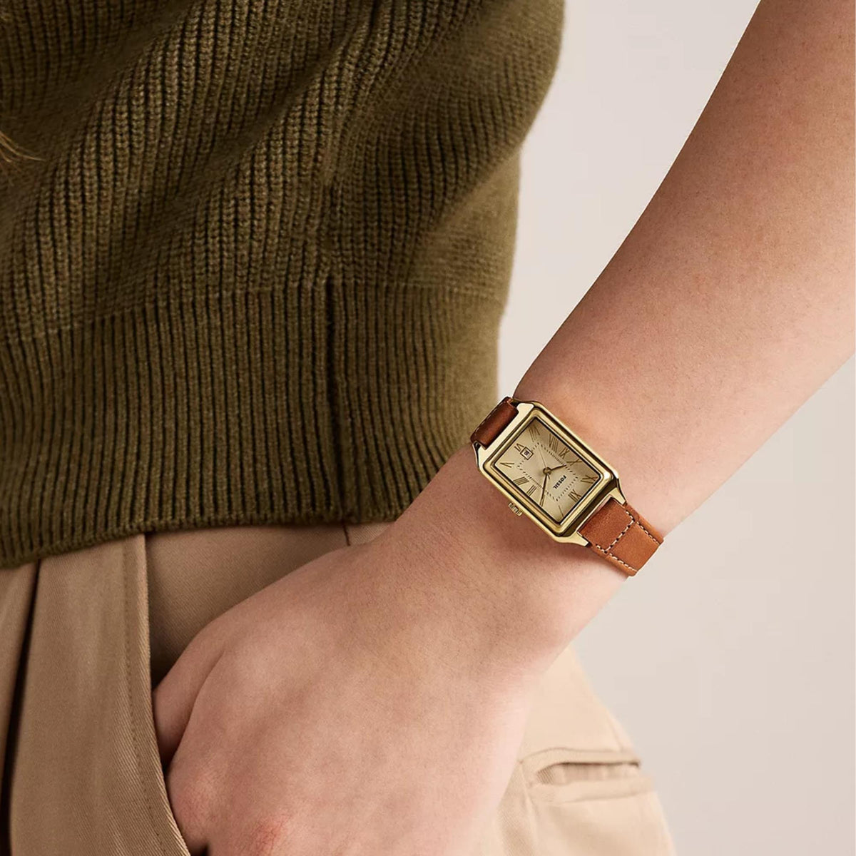Fossil Raquel ES5504 womens watch on wrist showing cream dial, gold-tone rectangular case, and brown leather strap