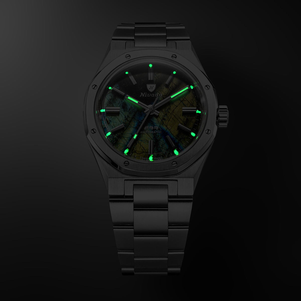 Nivada Grenchen F77 68054A77 close-up dial view highlighting glowing luminous hands and index markers in dark setting