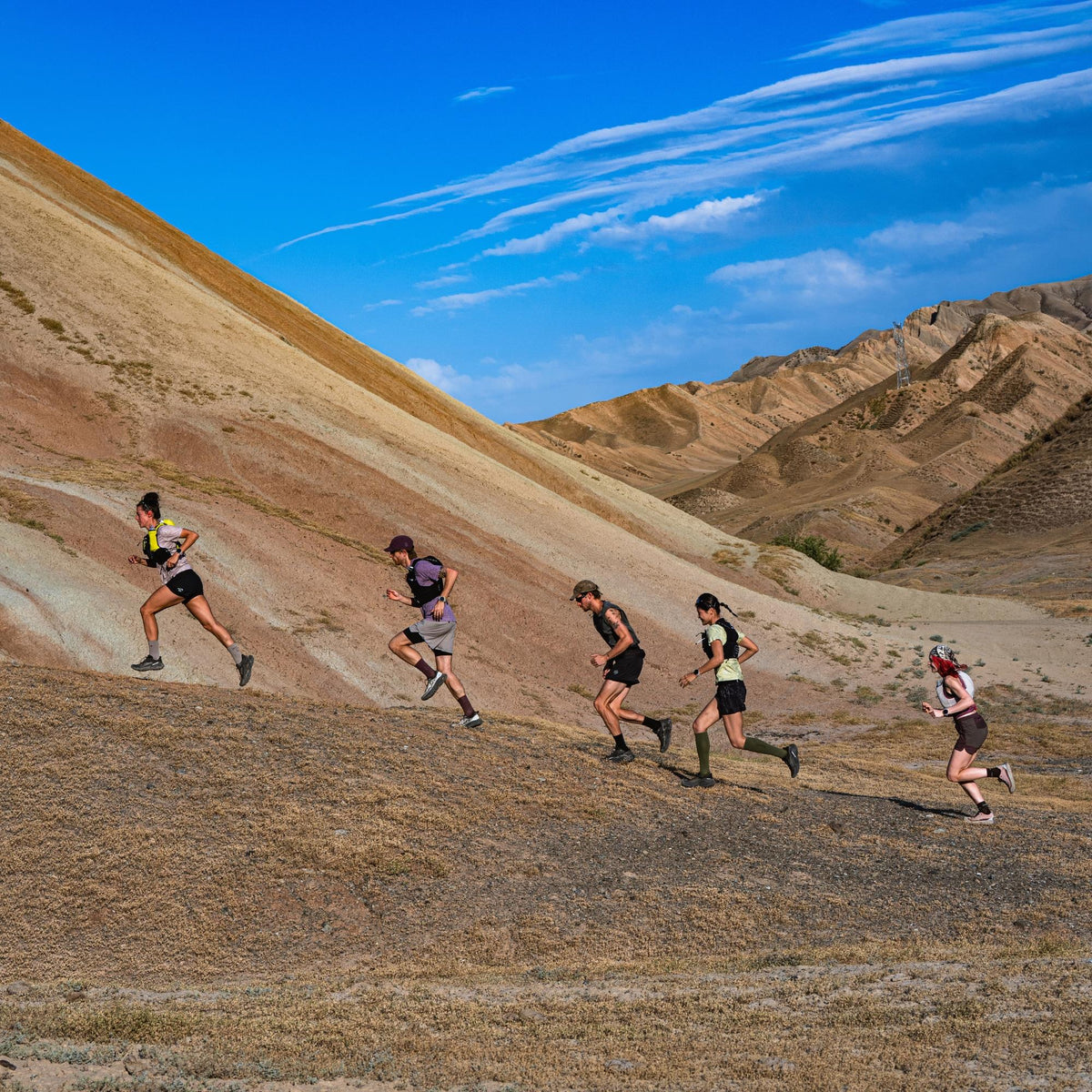 Suunto Race 3S SS051647000 lifestyle view showing runners moving along a desert mountain trail