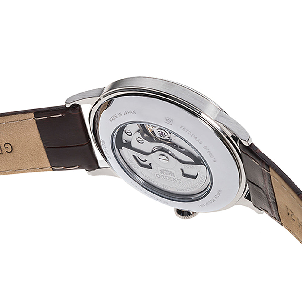 Orient Bambino watch case back with visible skeleton movement and brown leather strap