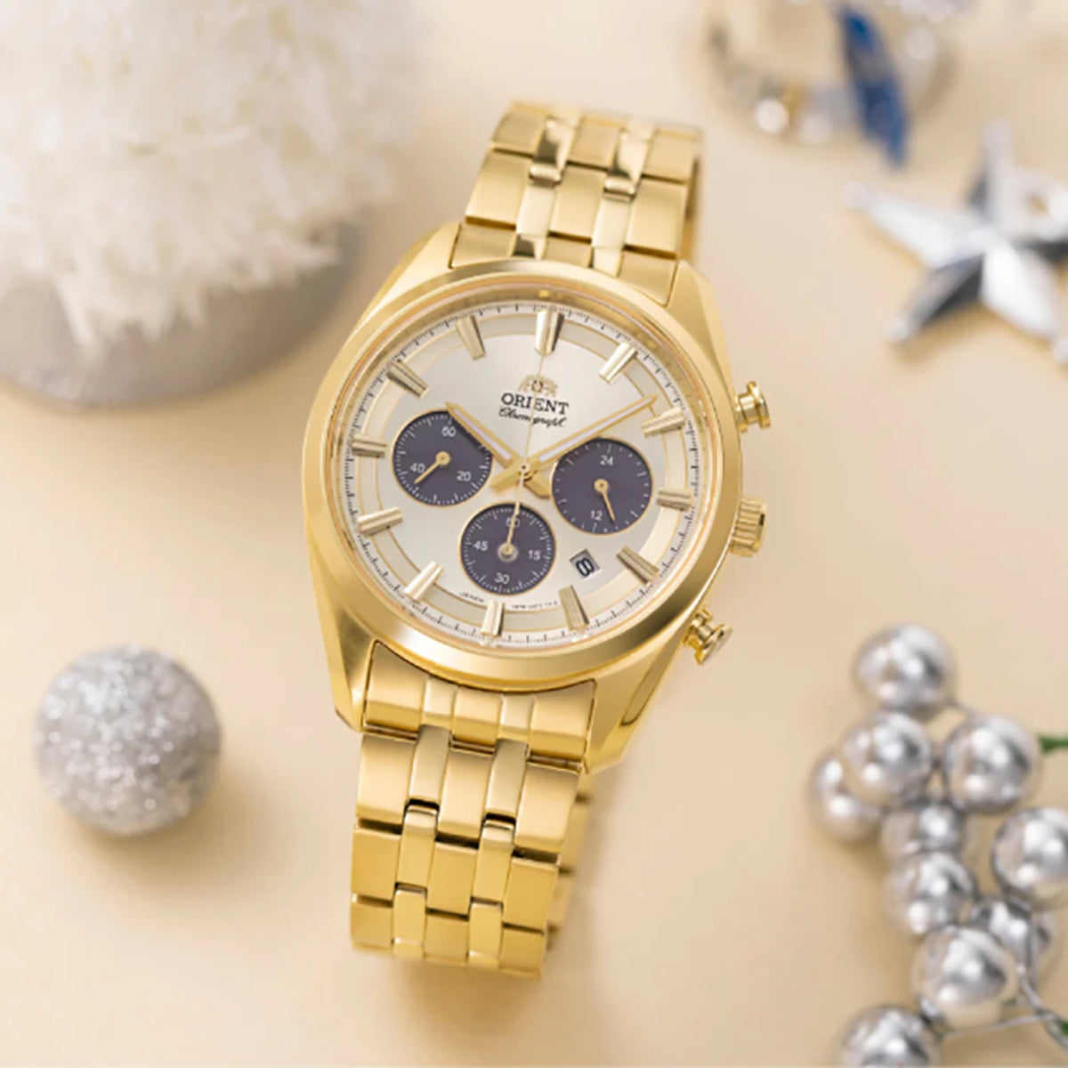 Gold solar chronograph watch with champagne dial, blue subdials, and linked steel bracelet.