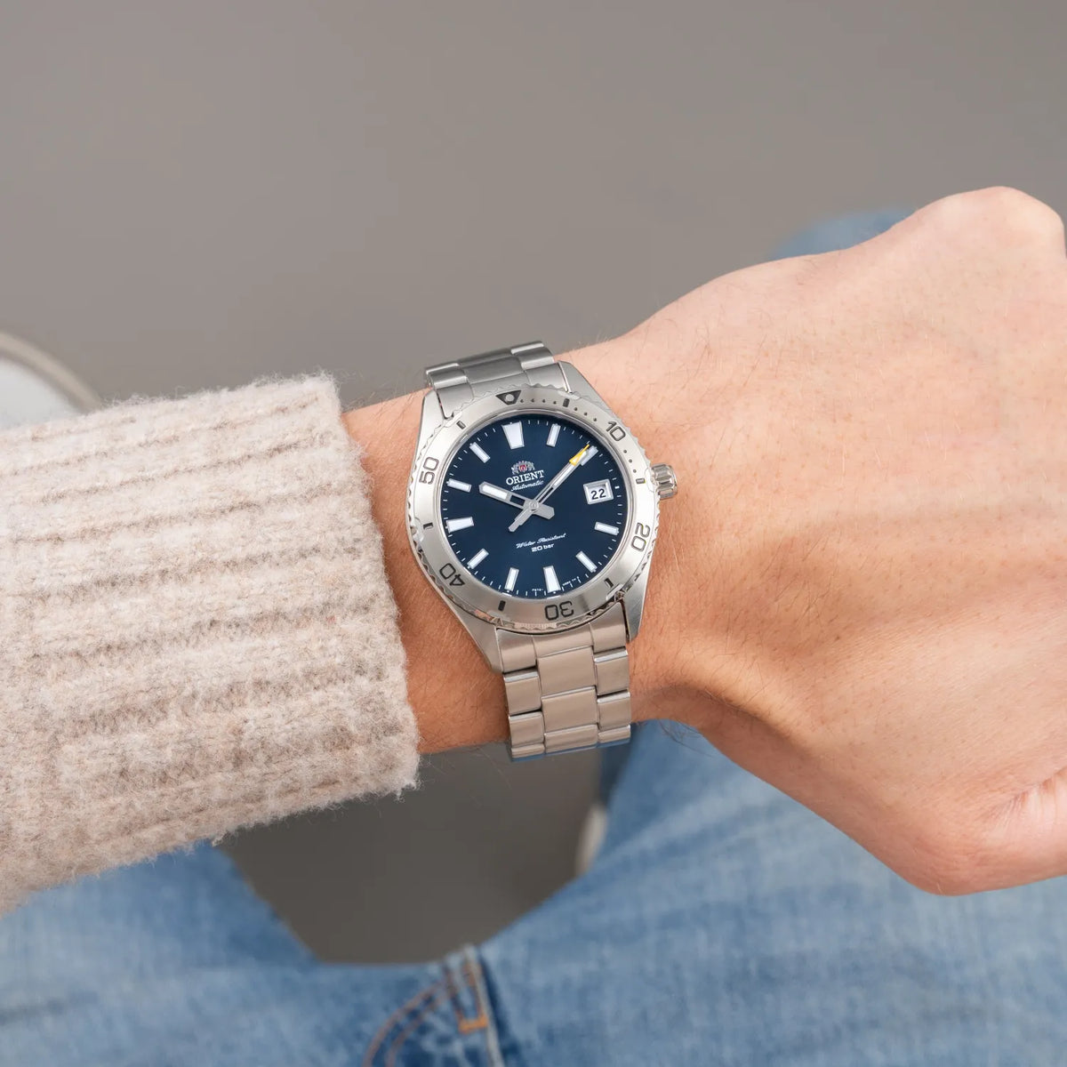 Orient mens automatic watch on wrist with blue dial and stainless steel bracelet