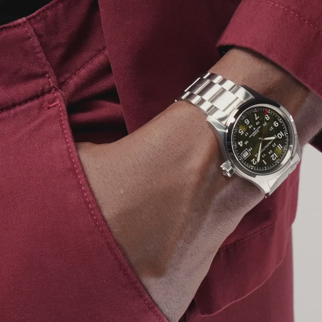 Hamilton Khaki Field H70455160 field wristwatch lifestyle wrist shot with hand in pocket highlighting green dial and metallic link bracelet