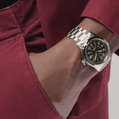 Hamilton Khaki Field H70455160 field wristwatch lifestyle wrist shot with hand in pocket highlighting green dial and metallic link bracelet