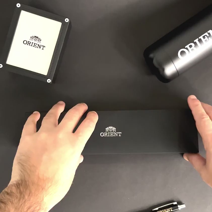 Hands opening the official presentation box for the Orient Bambino RA-AK0701S30B mechanical wrist watch
