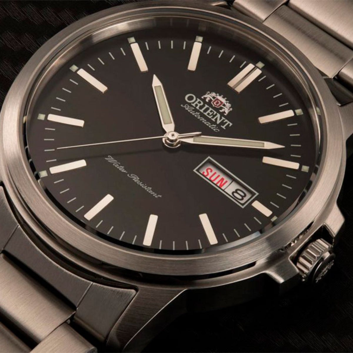 Close-up of Orient Contemporary RA-AA0C01B39B wristwatch showing black dial texture, luminous indices, and day-date display