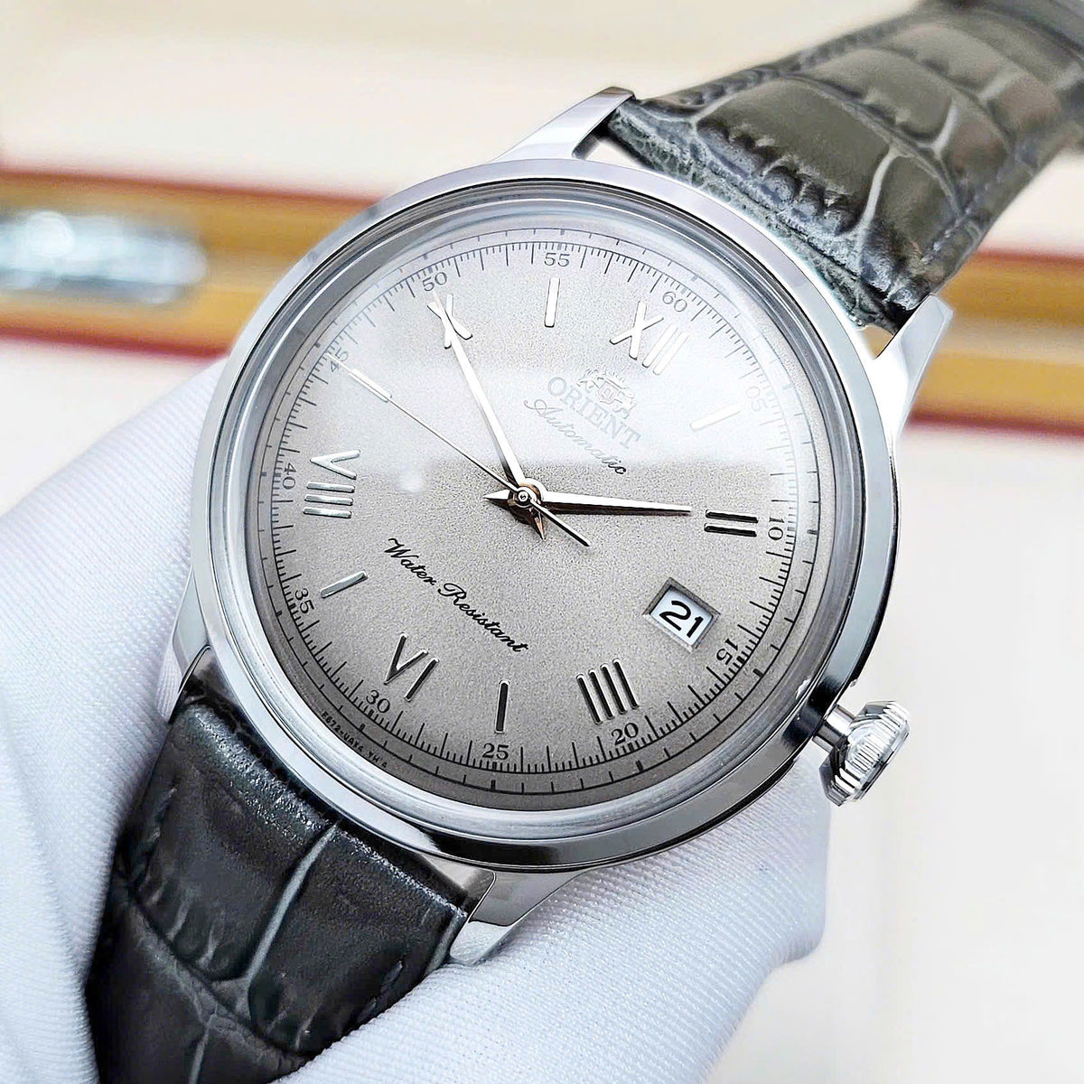 Orient Bambino Classic RA-AC0025N30B watch with green leather strap and stainless steel dial on a white background