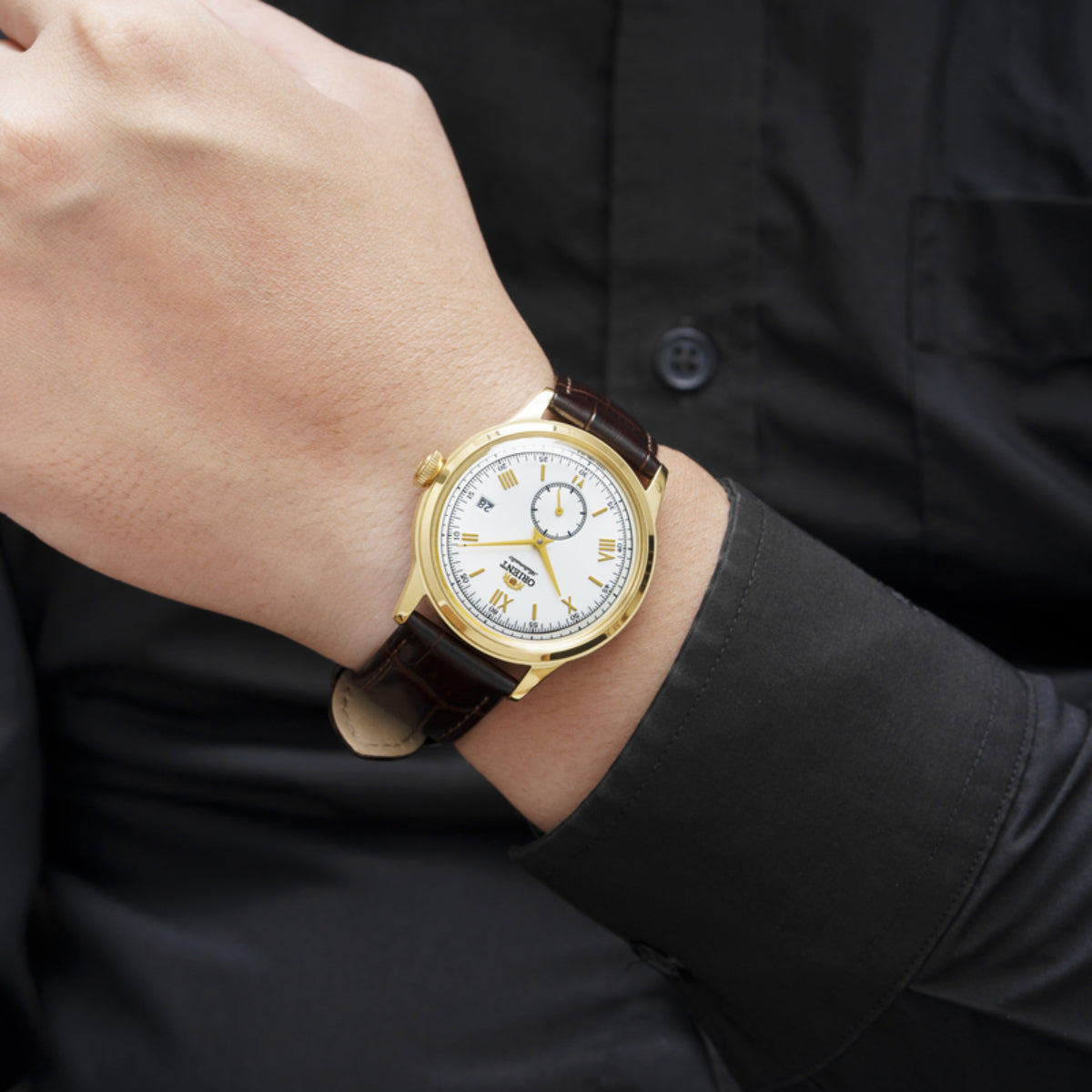 Orient Bambino 38mm watch worn on a wrist paired with a black button-down shirt sleeve