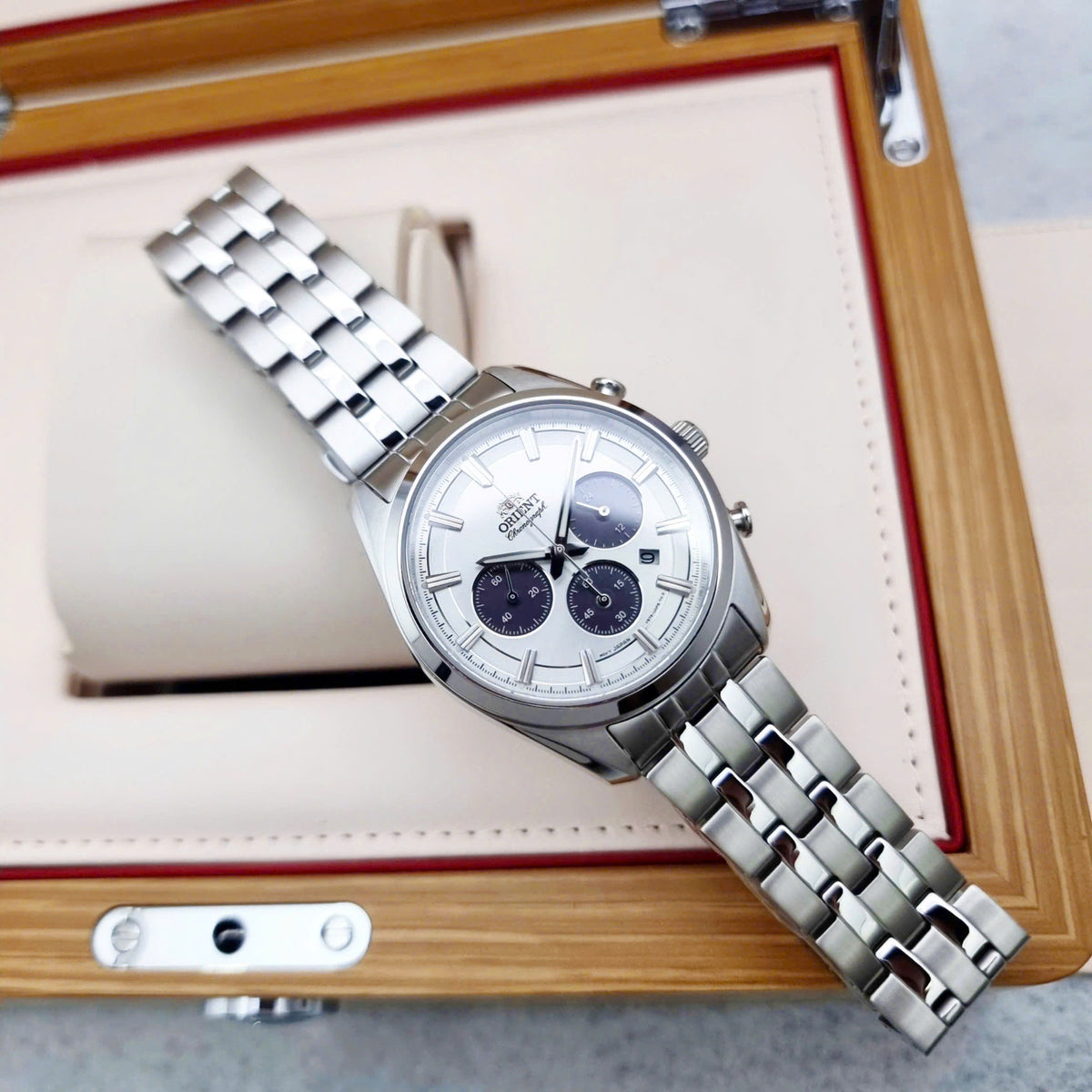 Men’s steel chronograph watch with white dial and subdials on a wooden card holder