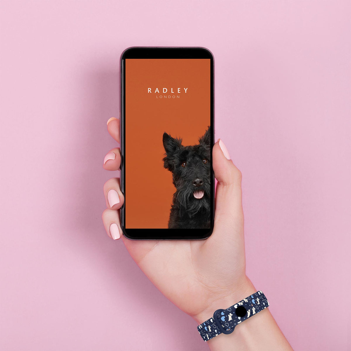 Hand wearing blue patterned silicone activity tracker strap, phone shows Radley app