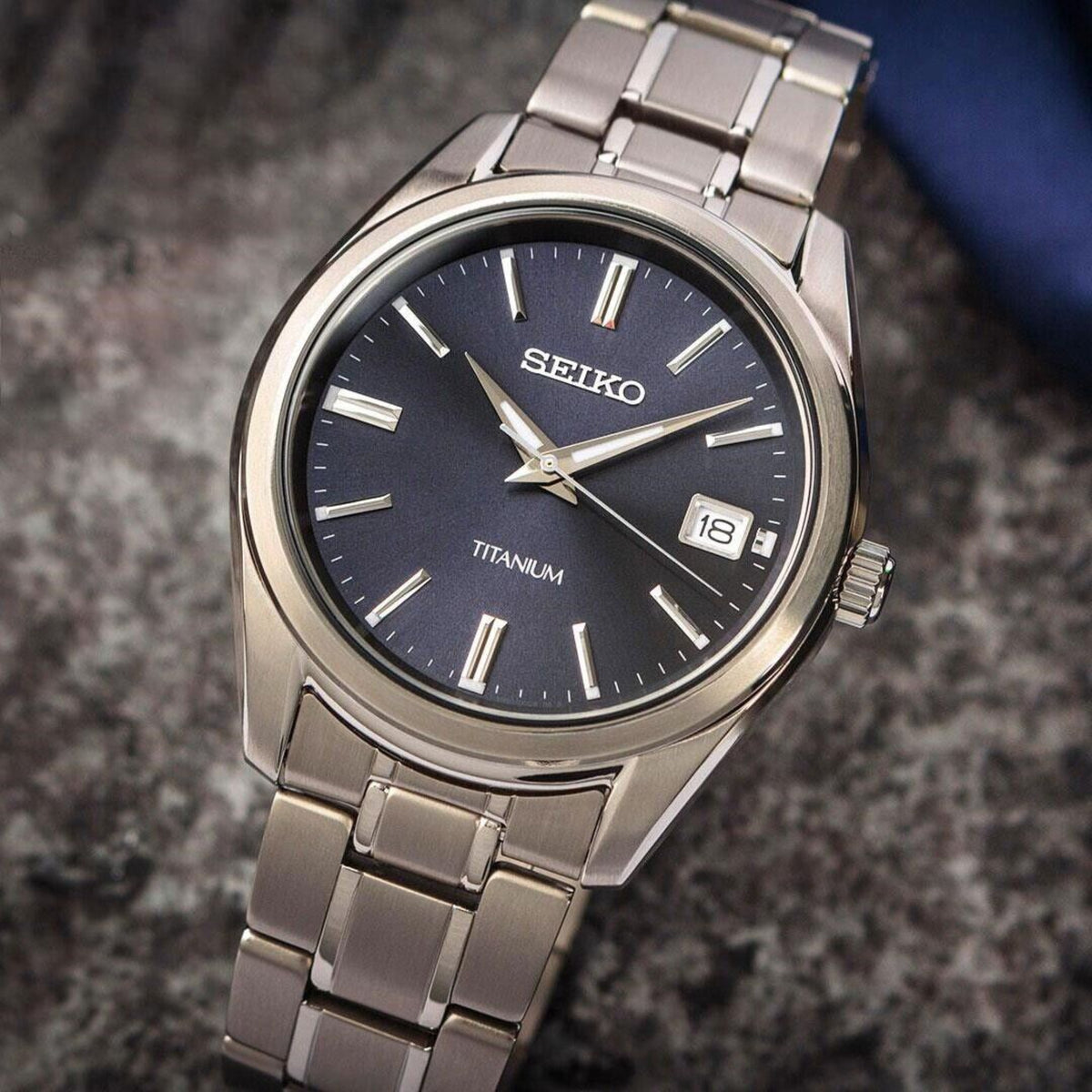 Close-up of Seiko SUR373P1 blue sunburst dial with date window and titanium bracelet