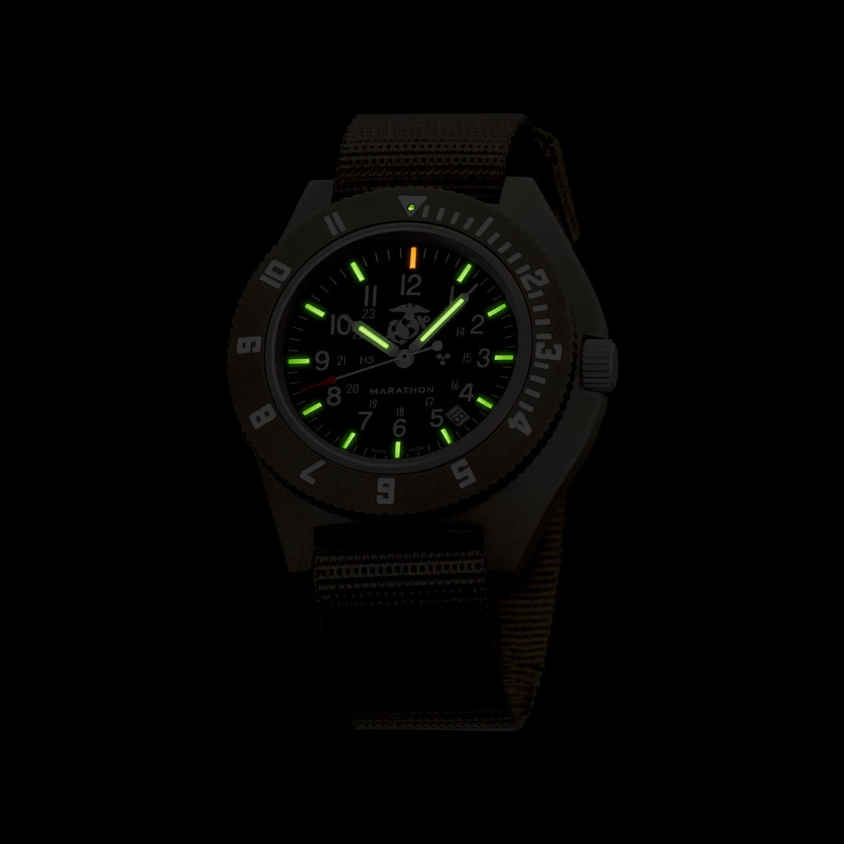 Marathon watch displaying glowing green tritium gas tubes on dial markers in darkness