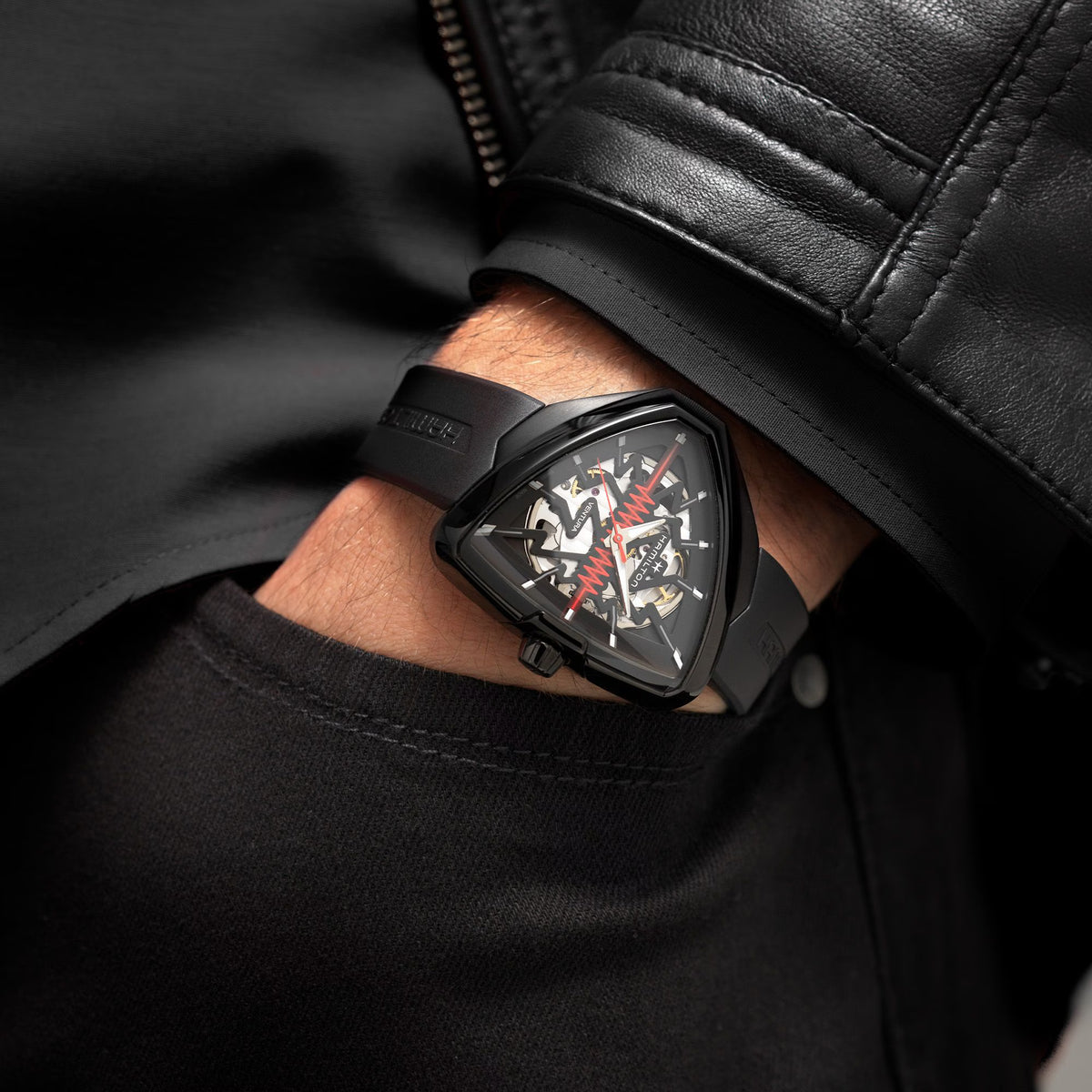 Men's black skeleton automatic watch on wrist with black rubber strap and red highlights