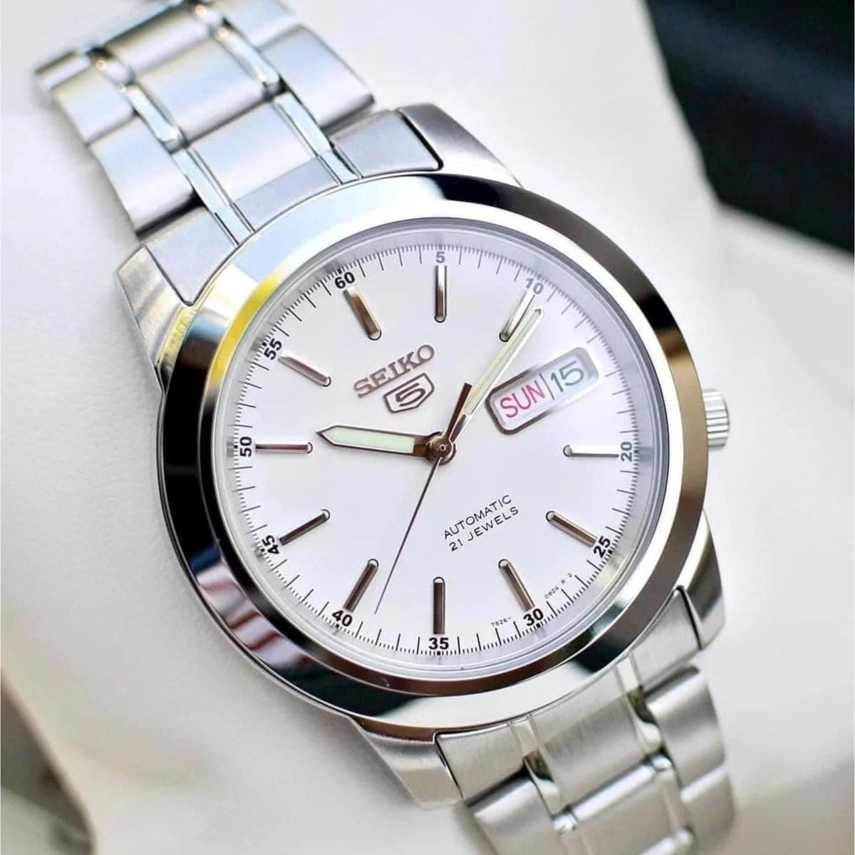 Seiko 5 Automatic SNKE49K1 angled close-up view of white dial resting on watch display cushion