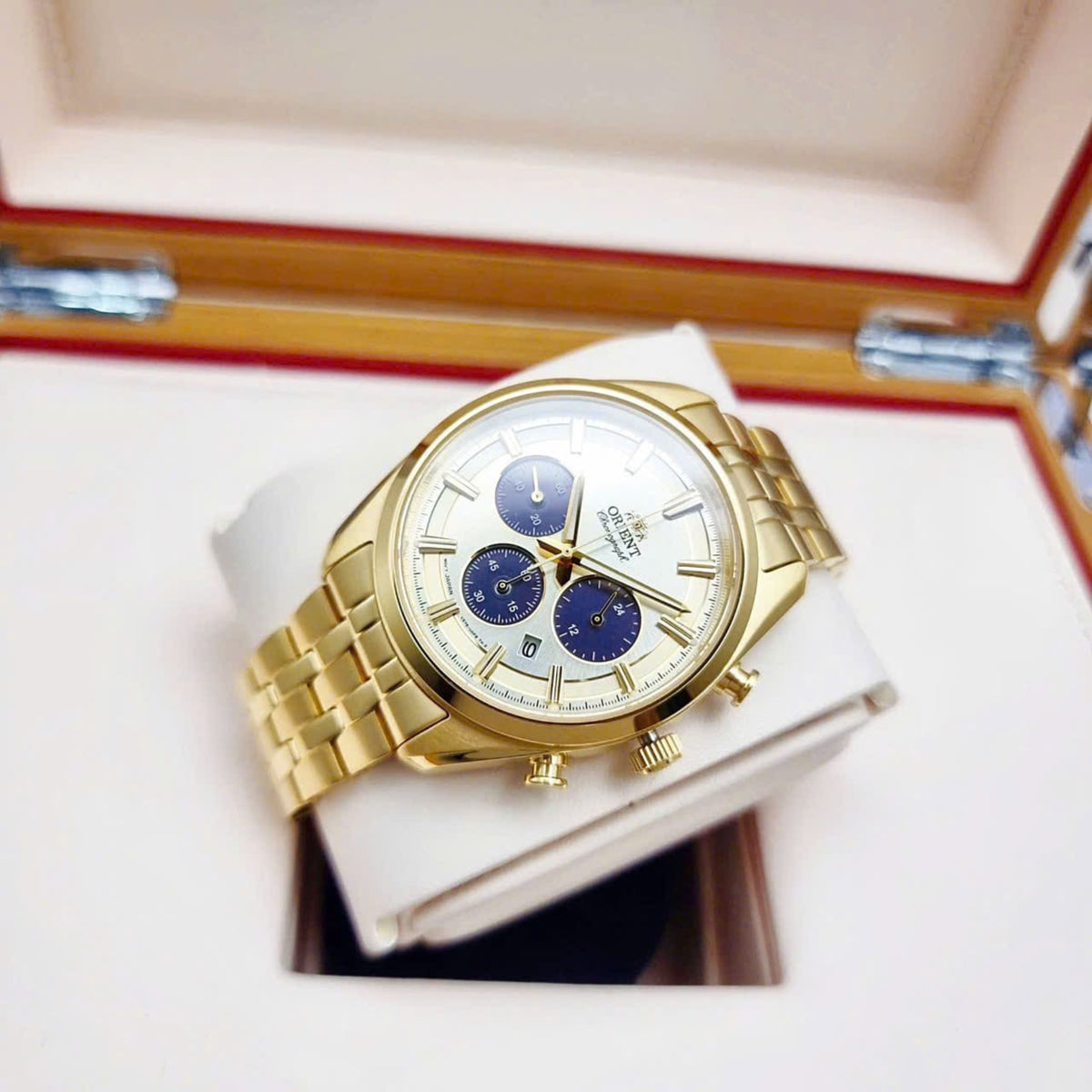 Gold chronograph wristwatch with champagne dial and blue subdials, steel bracelet.