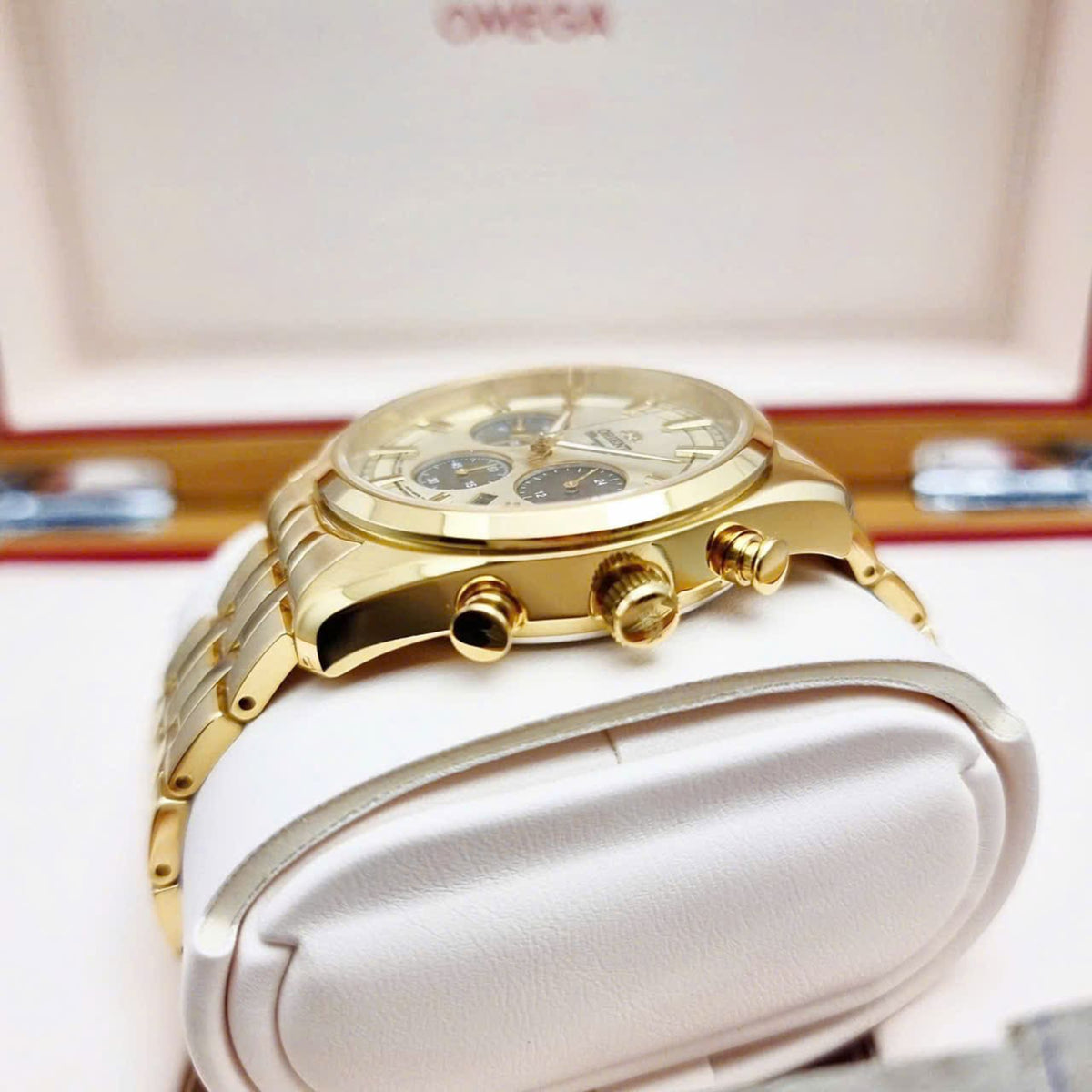 Gold watch case with crown details and bracelet links, viewed from the side on display.