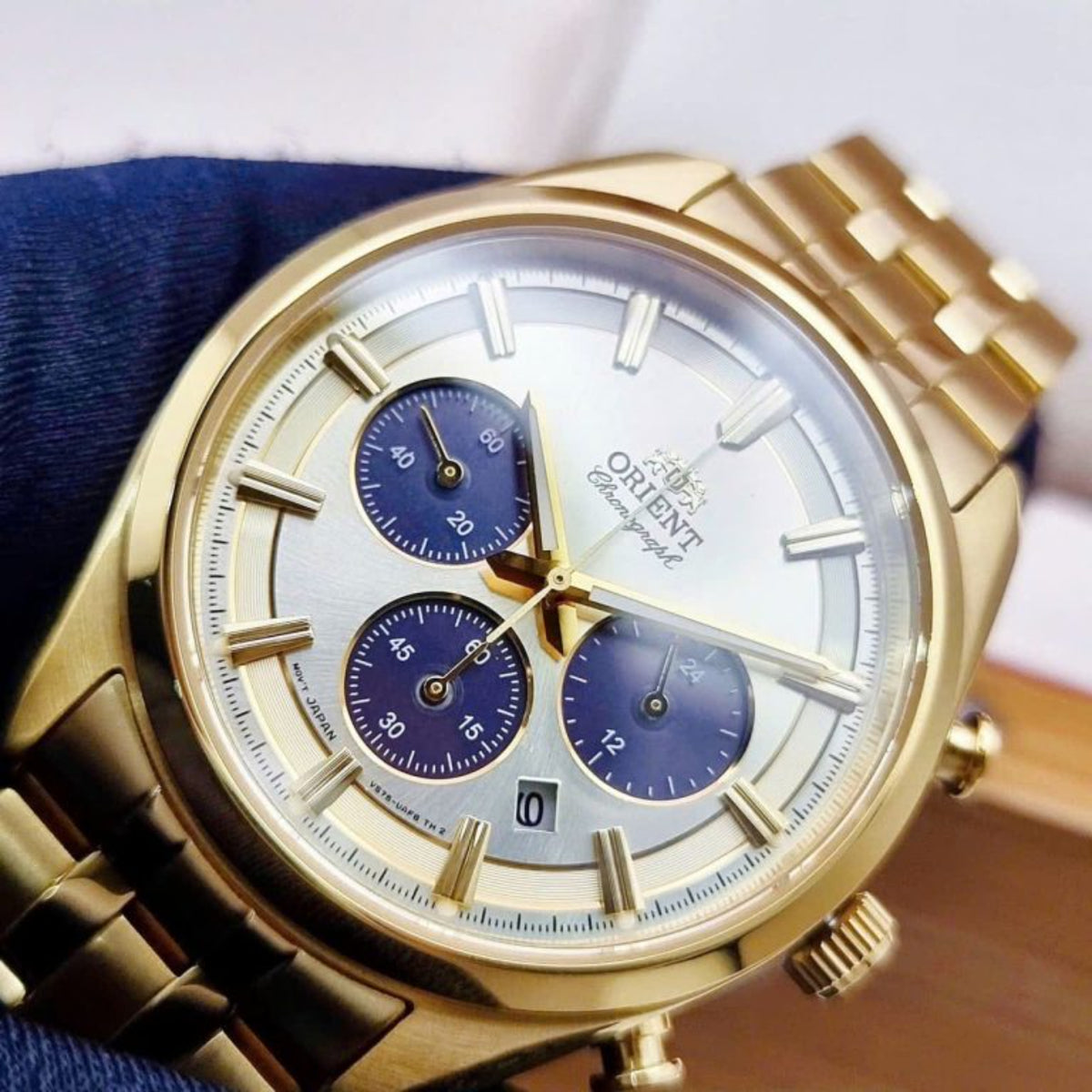 Close-up of gold solar chronograph watch face with champagne dial and blue subdials.