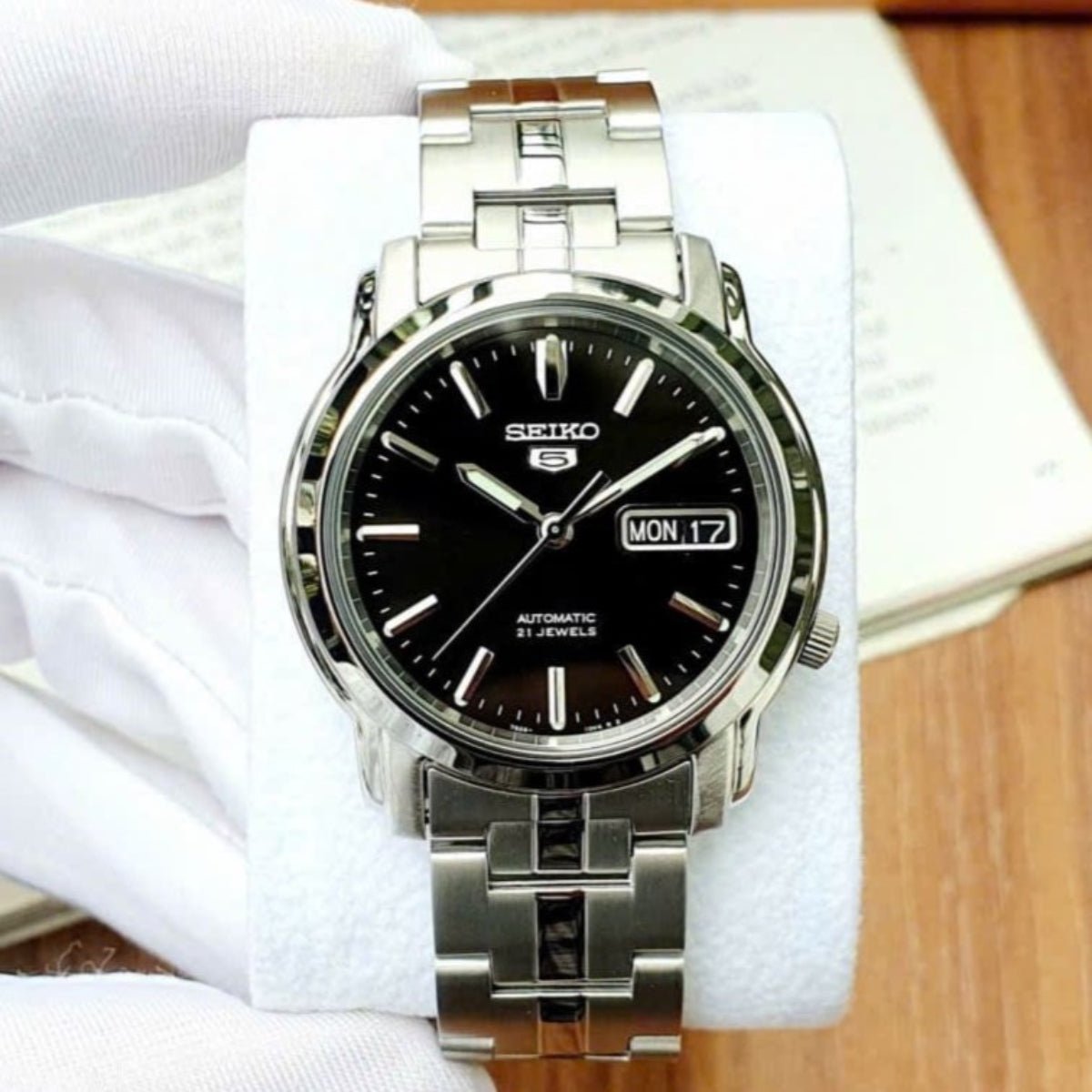 Seiko 5 Classic SNKK71K1 straight front perspective with black dial resting on display cushion