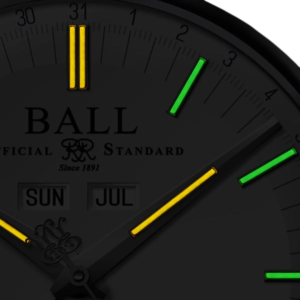 Black dial watch close-up with yellow and green hour markers and date window