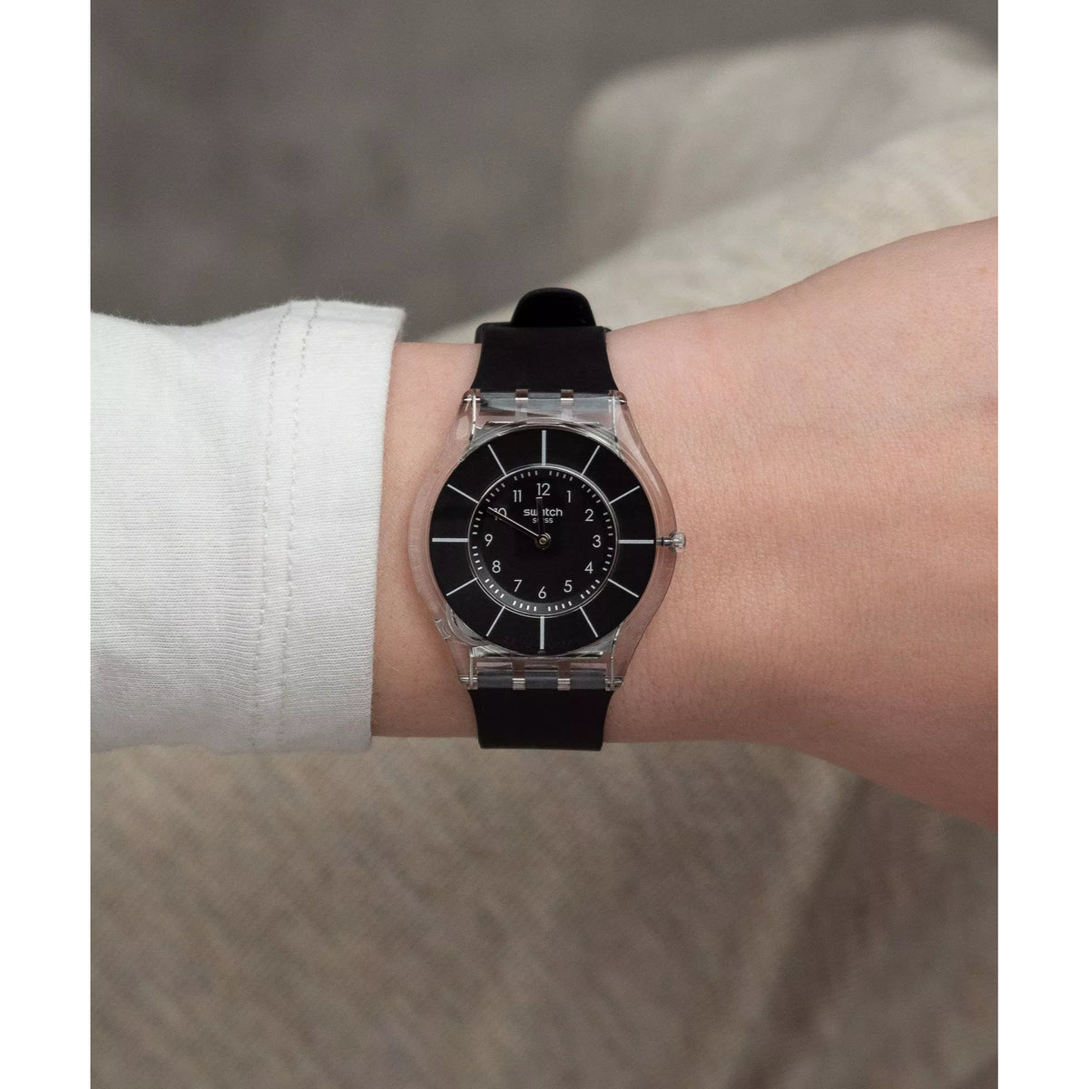 Black dial wristwatch on wrist, silver case and black strap visible