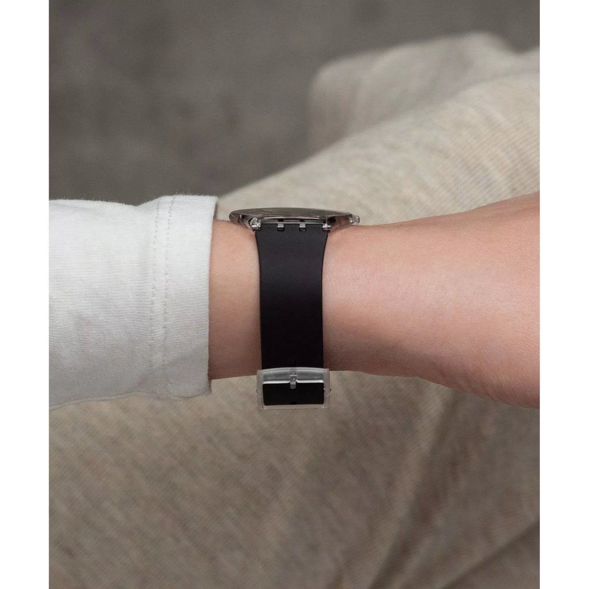 Black silicone strap wristwatch with silver buckle on light shirt cuff