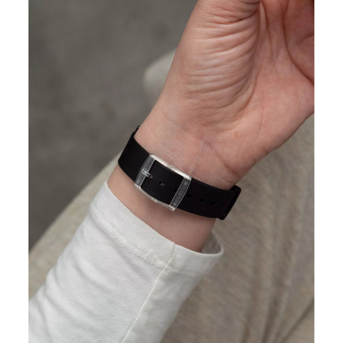 Black silicone strap wristwatch close-up on wrist with silver clasp