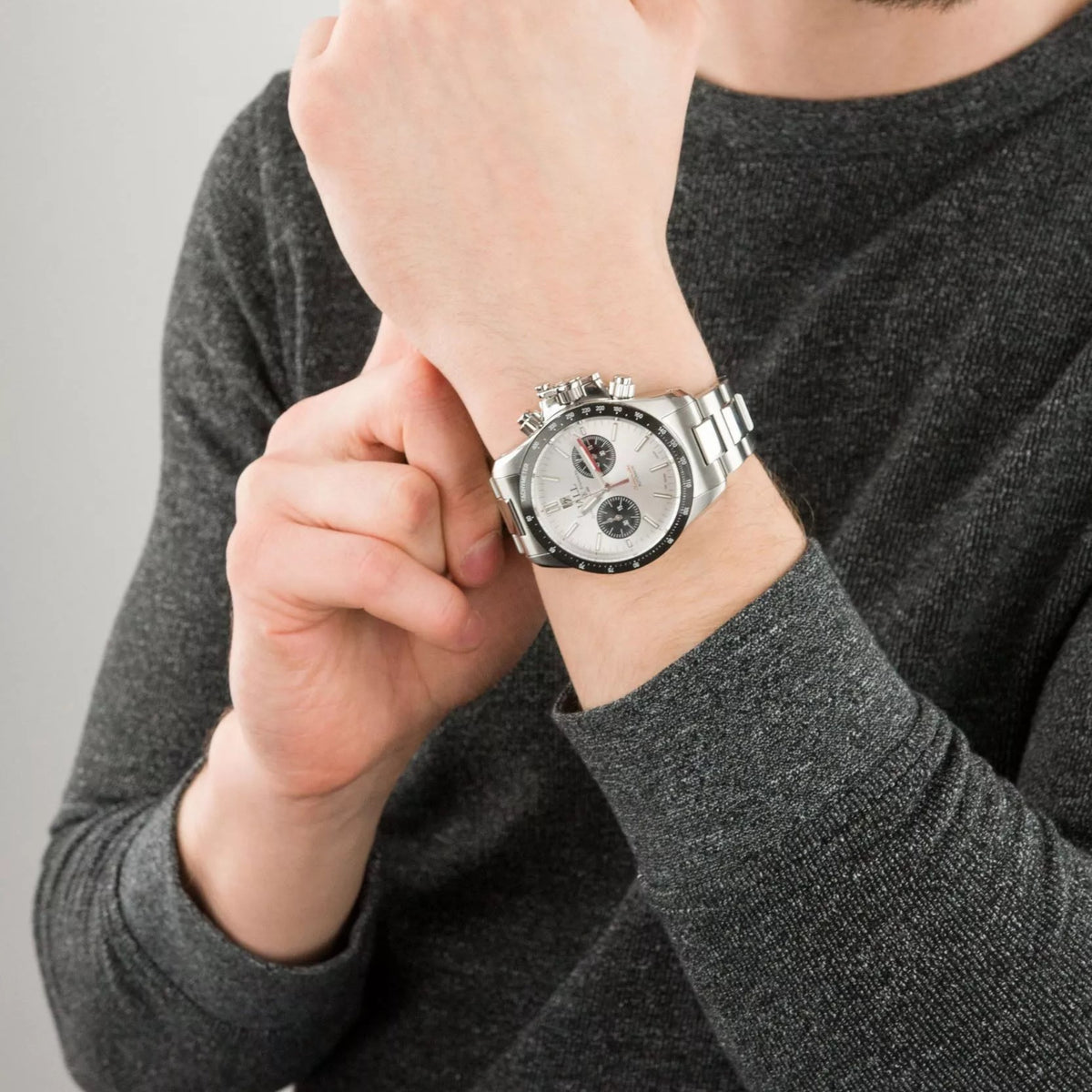 Men's wrist wearing a stainless steel chronograph automatic watch with white dial