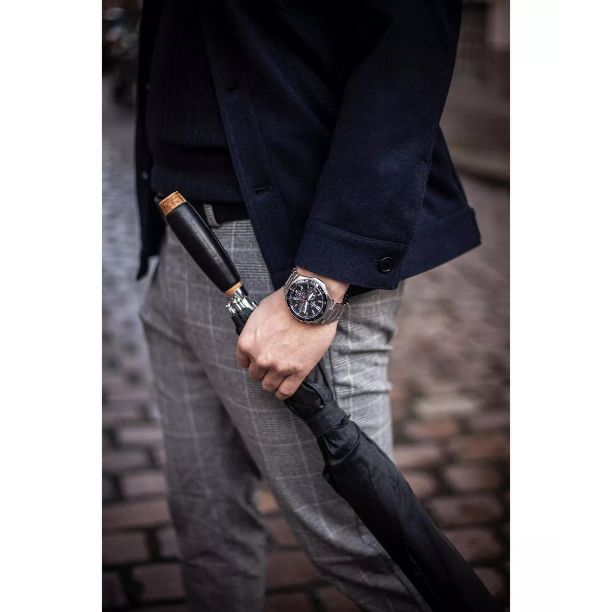 Men’s stainless steel solar chronograph watch worn with dark suit jacket sleeve and bracelet